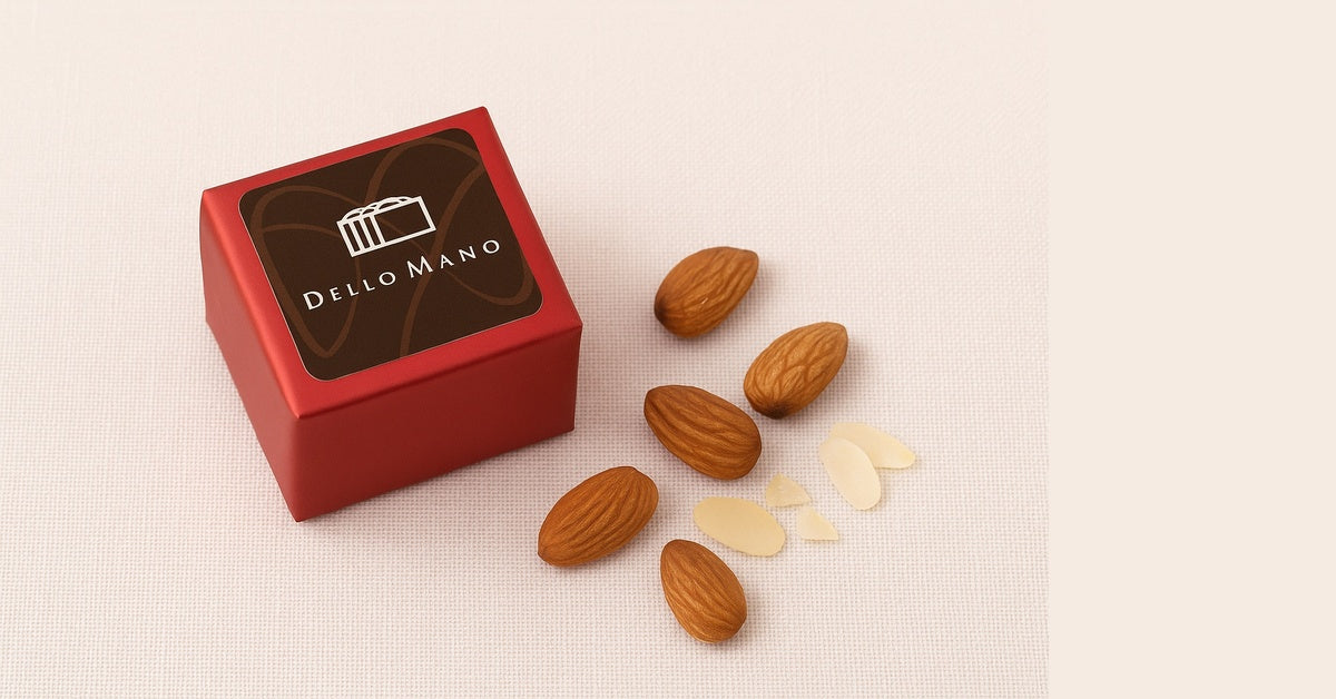 Dello Mano red gift box with whole almonds and almond flakes on a soft linen background, styled for handmade gluten-friendly brownie delivery.