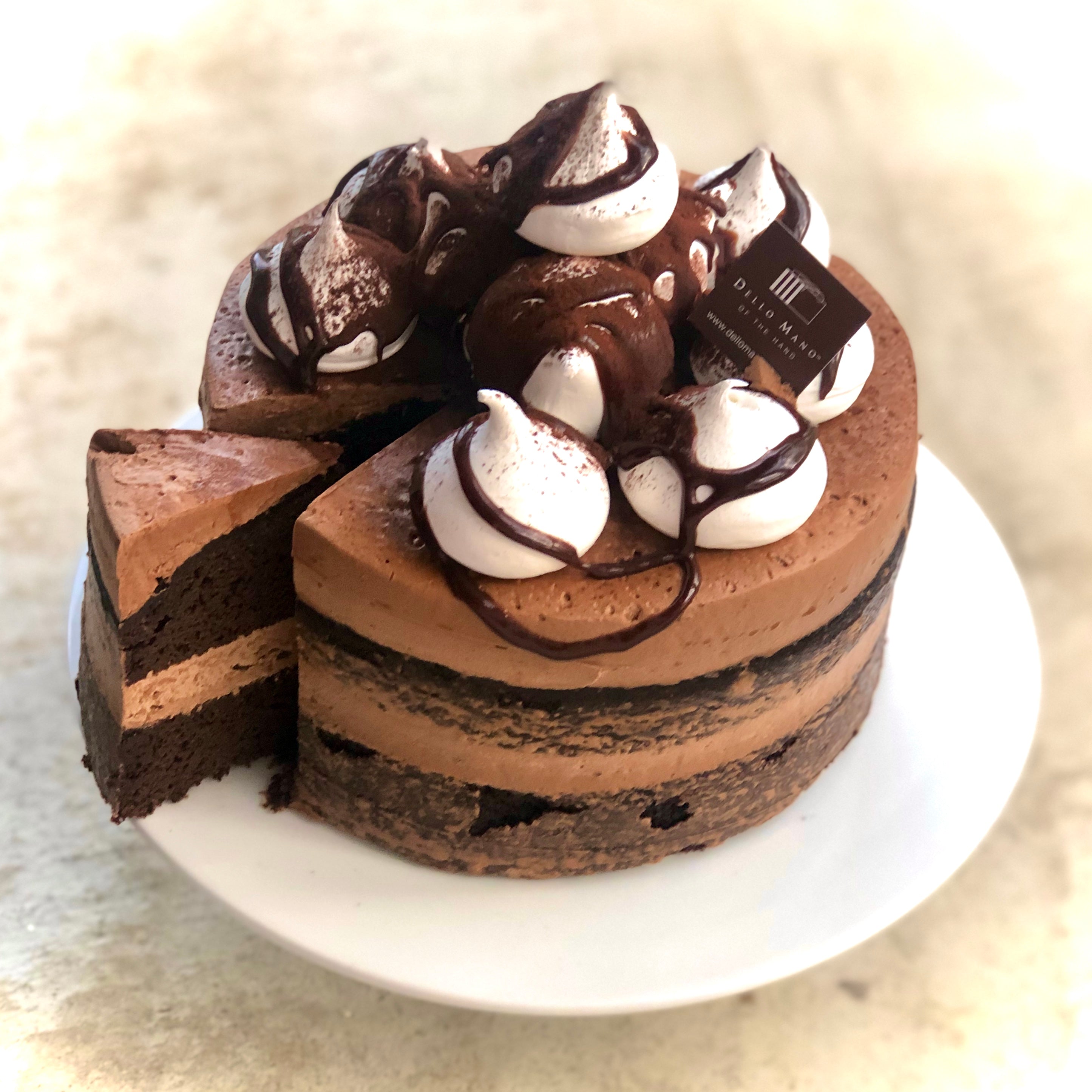 A chocolate mud cake with slice being removed