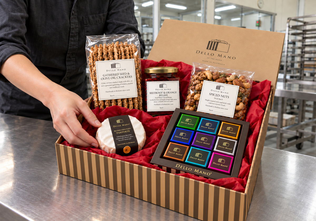 A packer places panforte into the red tissue-lined Dello Mano Christmas Celebration Hamper, alongside brownies, crackers, relish and spiced nuts in the West End kitchen.