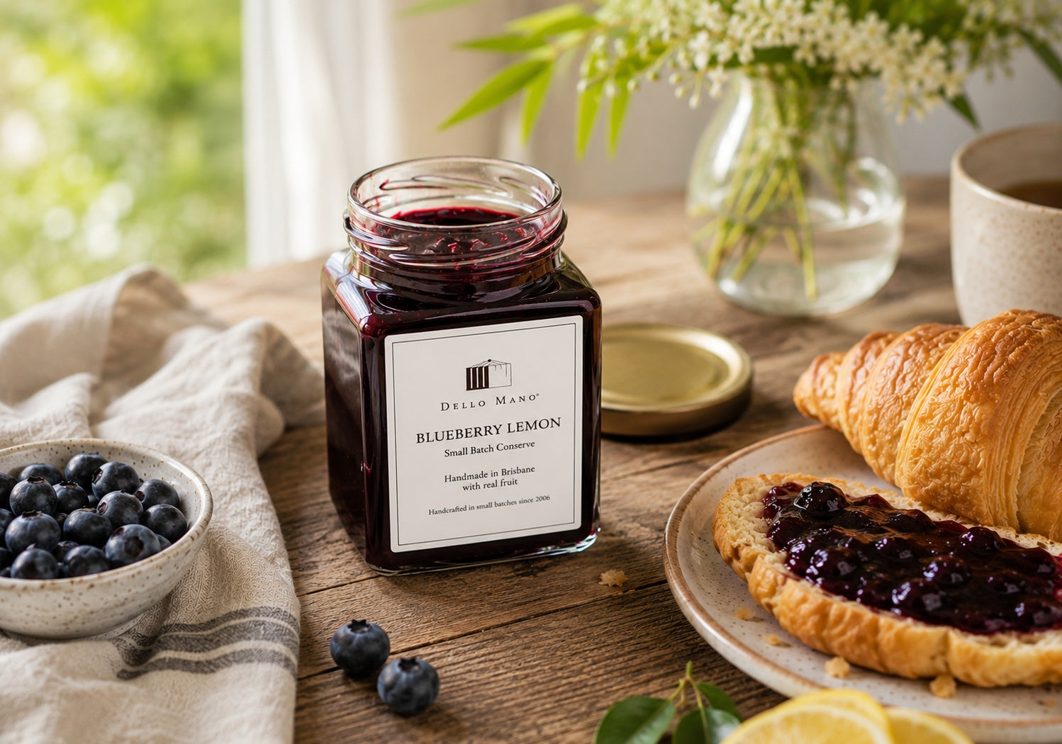 Blueberry Lemon Jam by Dello Mano served with a croissant, fresh blueberries and lemon in a calm natural light breakfast setting.