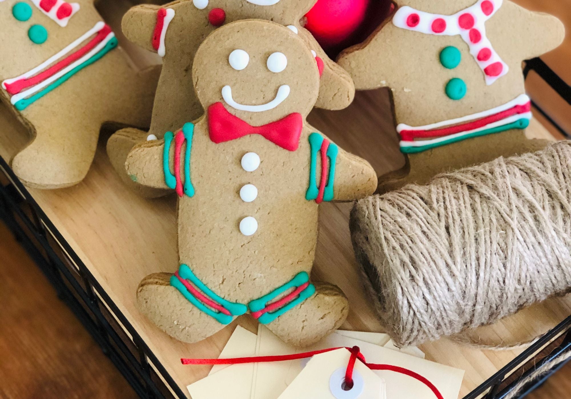 Decorative gingerbread man cookies with red and green icing on a wooden surface.