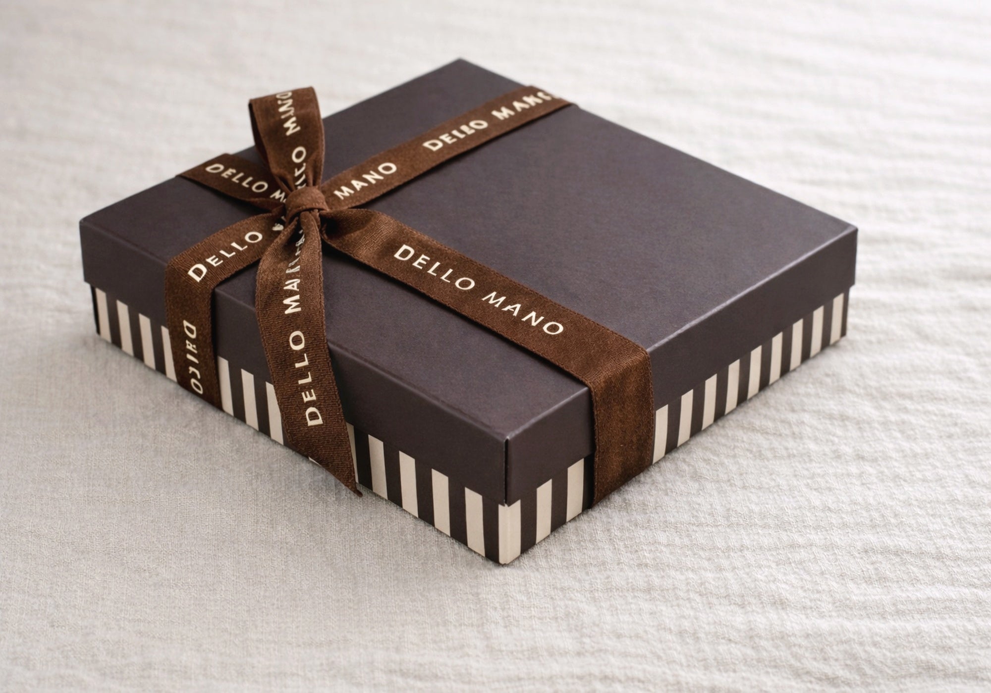 Handmade Dello Mano chocolate gift box wrapped in brown ribbon on neutral linen background, structured for safe delivery across Australia