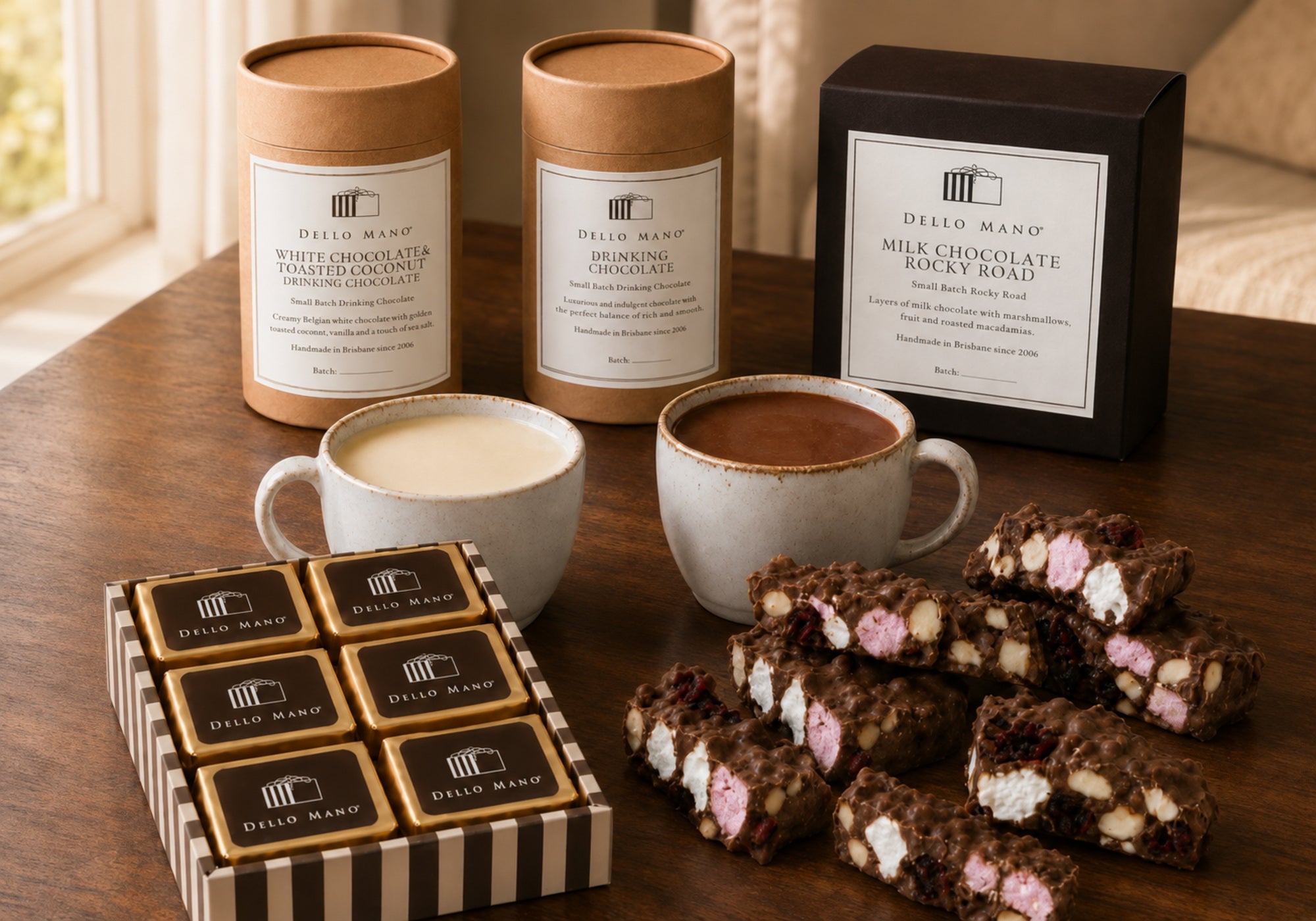 Dello Mano White Chocolate and Toasted Coconut Drinking Chocolate, Dark Drinking Chocolate, brownies and Milk Chocolate Rocky Road on a timber table