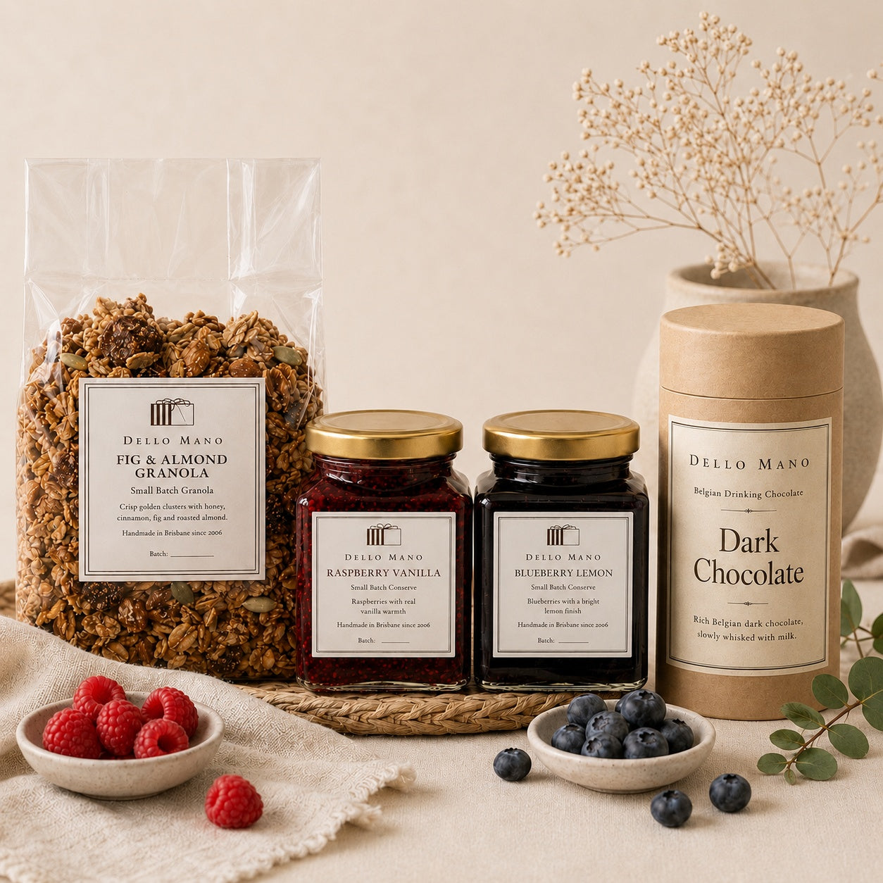 Dello Mano fig and almond granola, raspberry vanilla conserve, blueberry lemon conserve and dark drinking chocolate styled on soft neutral linen.