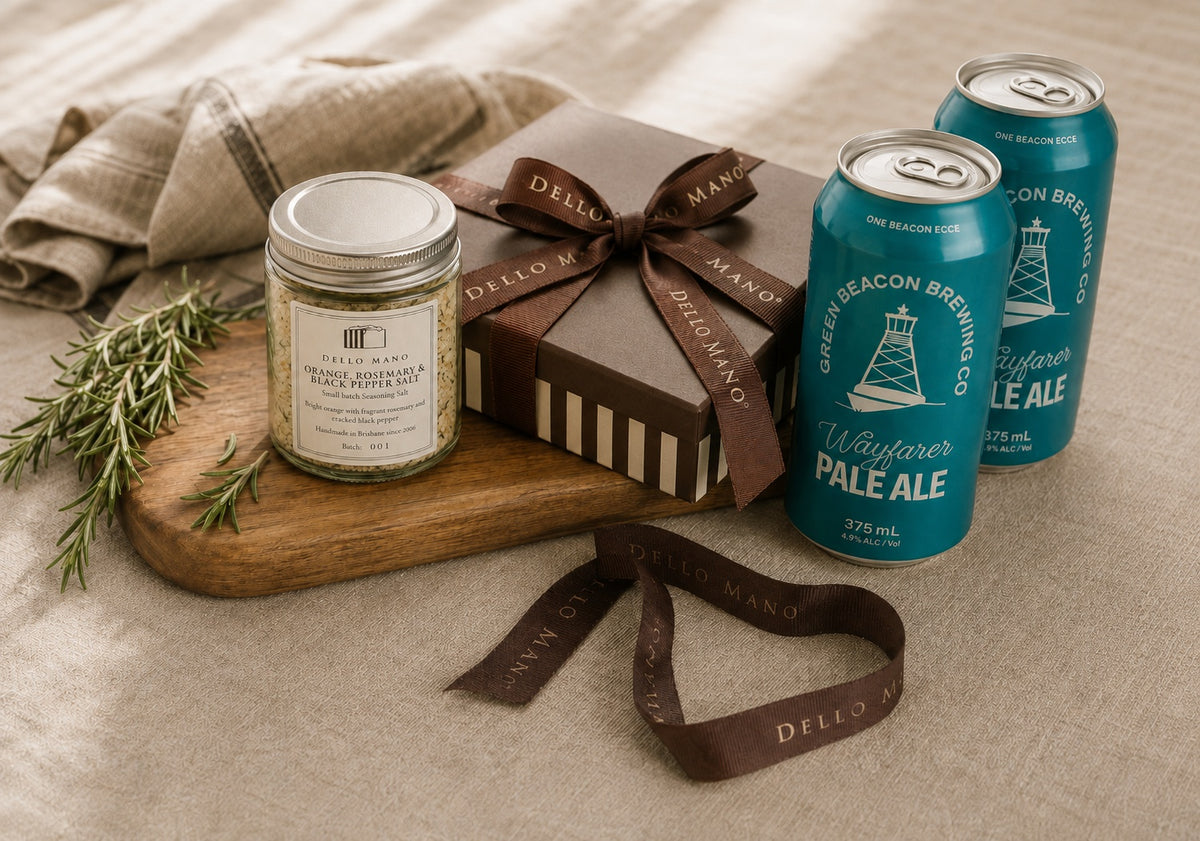 Dello Mano Father’s Day gift scene with brownie gift box, Green Beacon pale ale cans and Orange, Rosemary & Black Pepper Salt on natural linen.