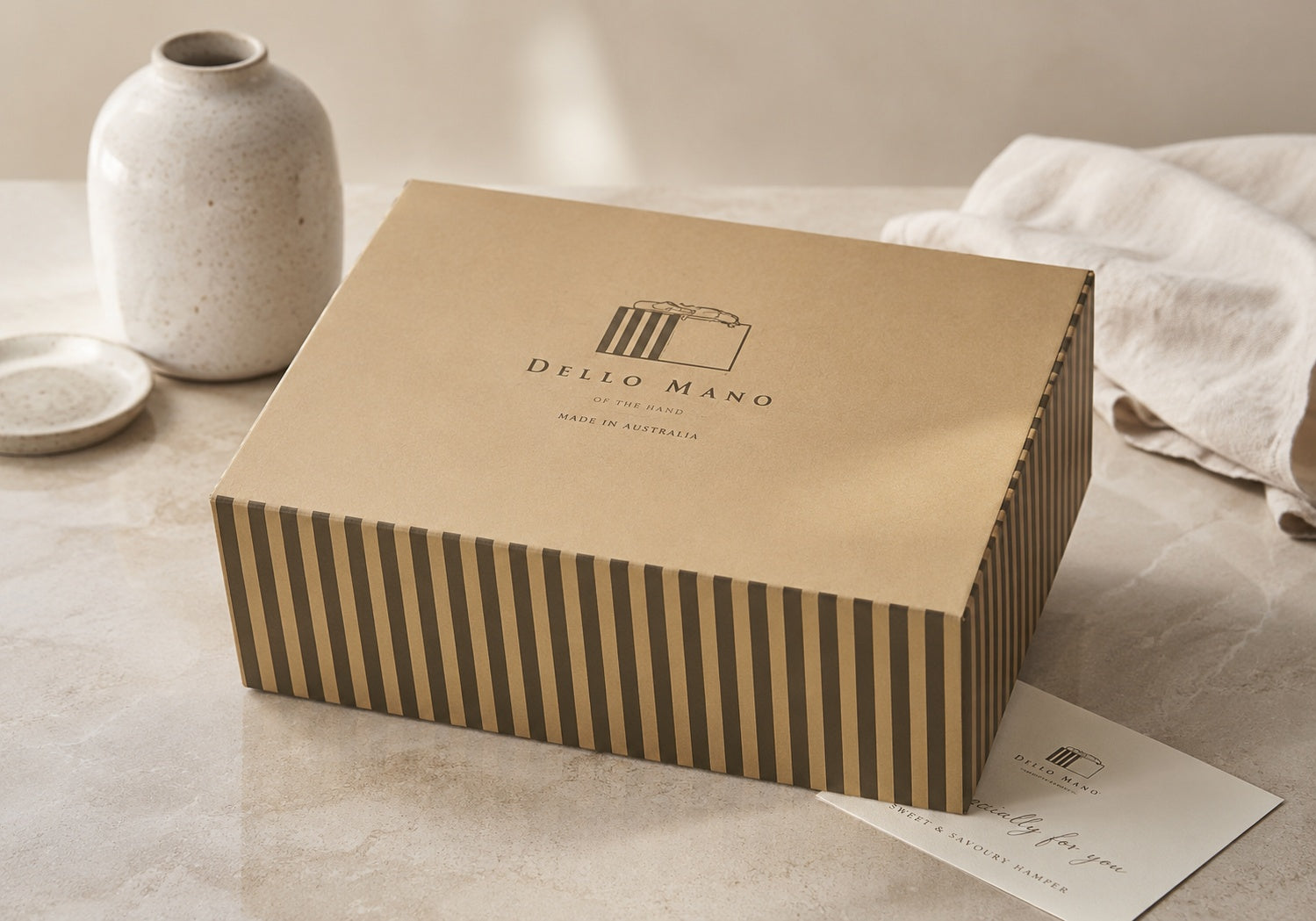 Closed Dello Mano Sweet & Savoury Hamper gift box with striped sides and a gift message card, ready for delivery across Australia.