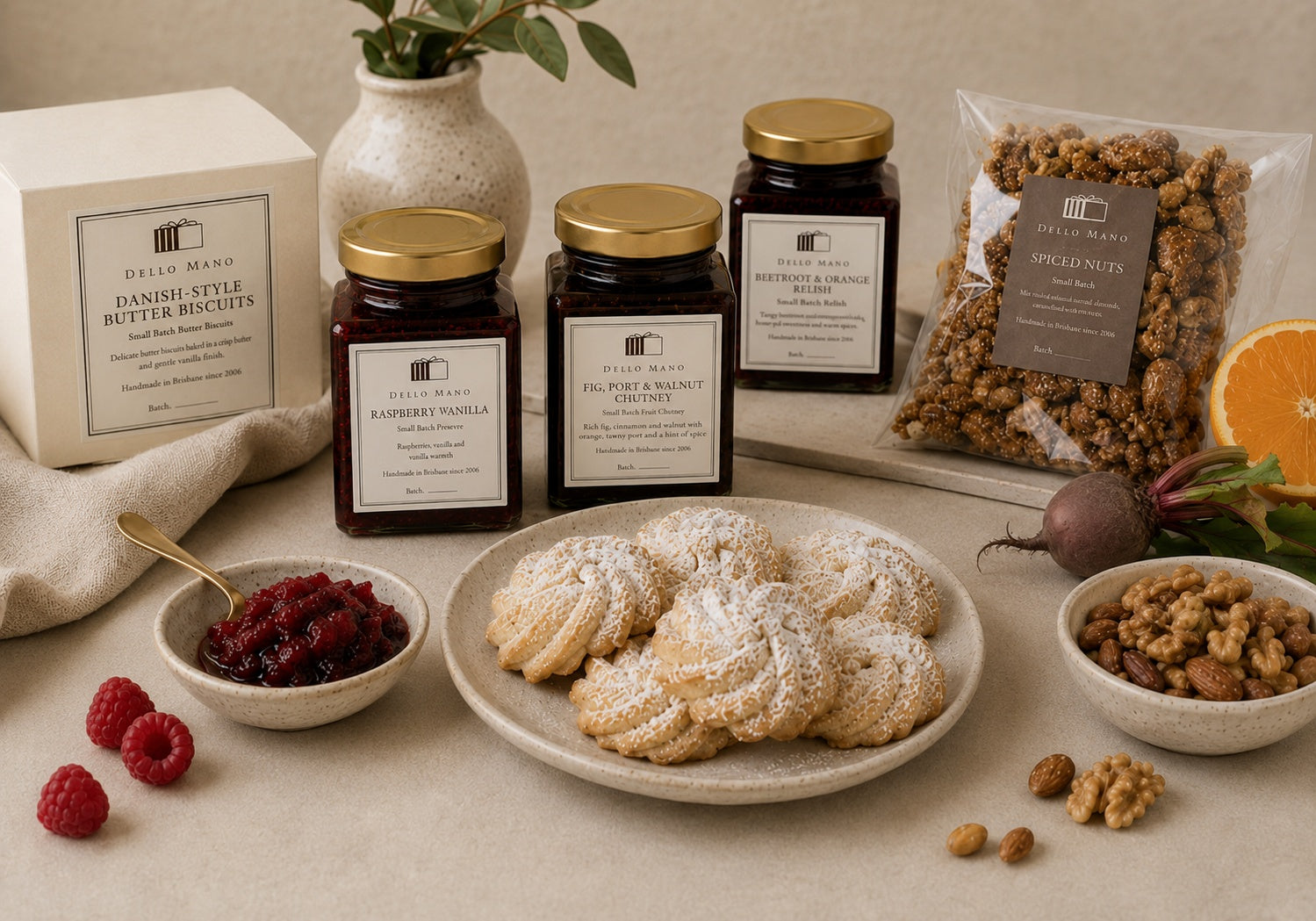 Dello Mano Sweet & Savoury Hamper range with Raspberry Vanilla Jam, Fig Port and Walnut Chutney, Beetroot and Orange Relish, Danish-style butter biscuits and spiced nuts displayed with biscuits, raspberries and fresh beetroot.