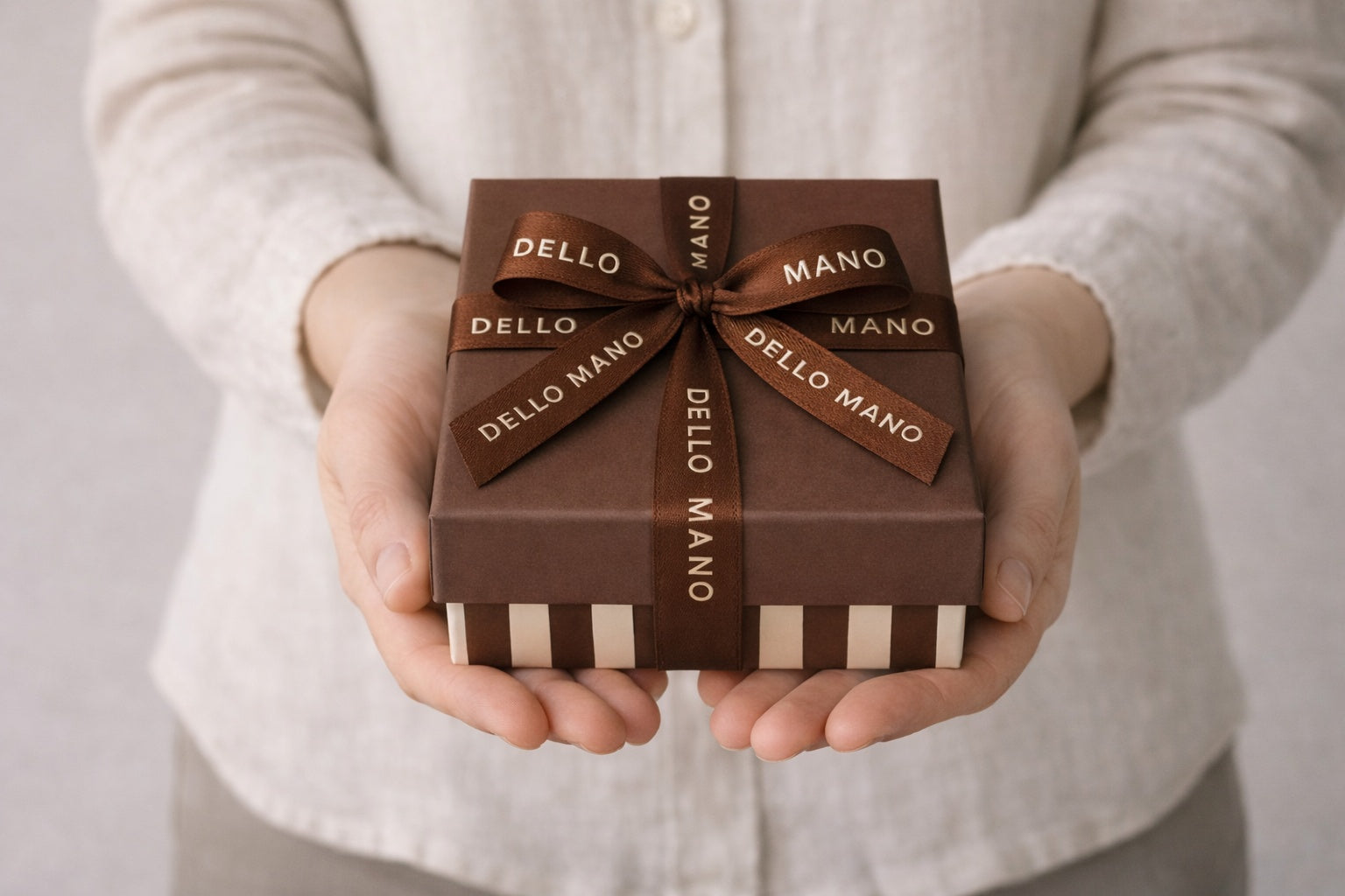 Hand holding Dello Mano thank you gift box with ribbon, showcasing handmade chocolate gifting