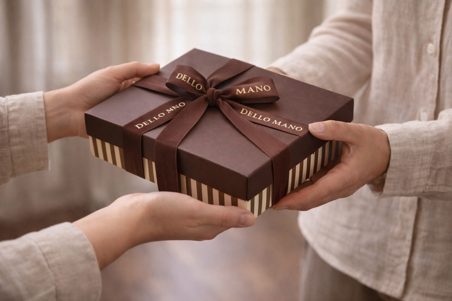 Hands exchanging a Dello Mano brownie gift box with brown ribbon, styled for thoughtful gifting moments