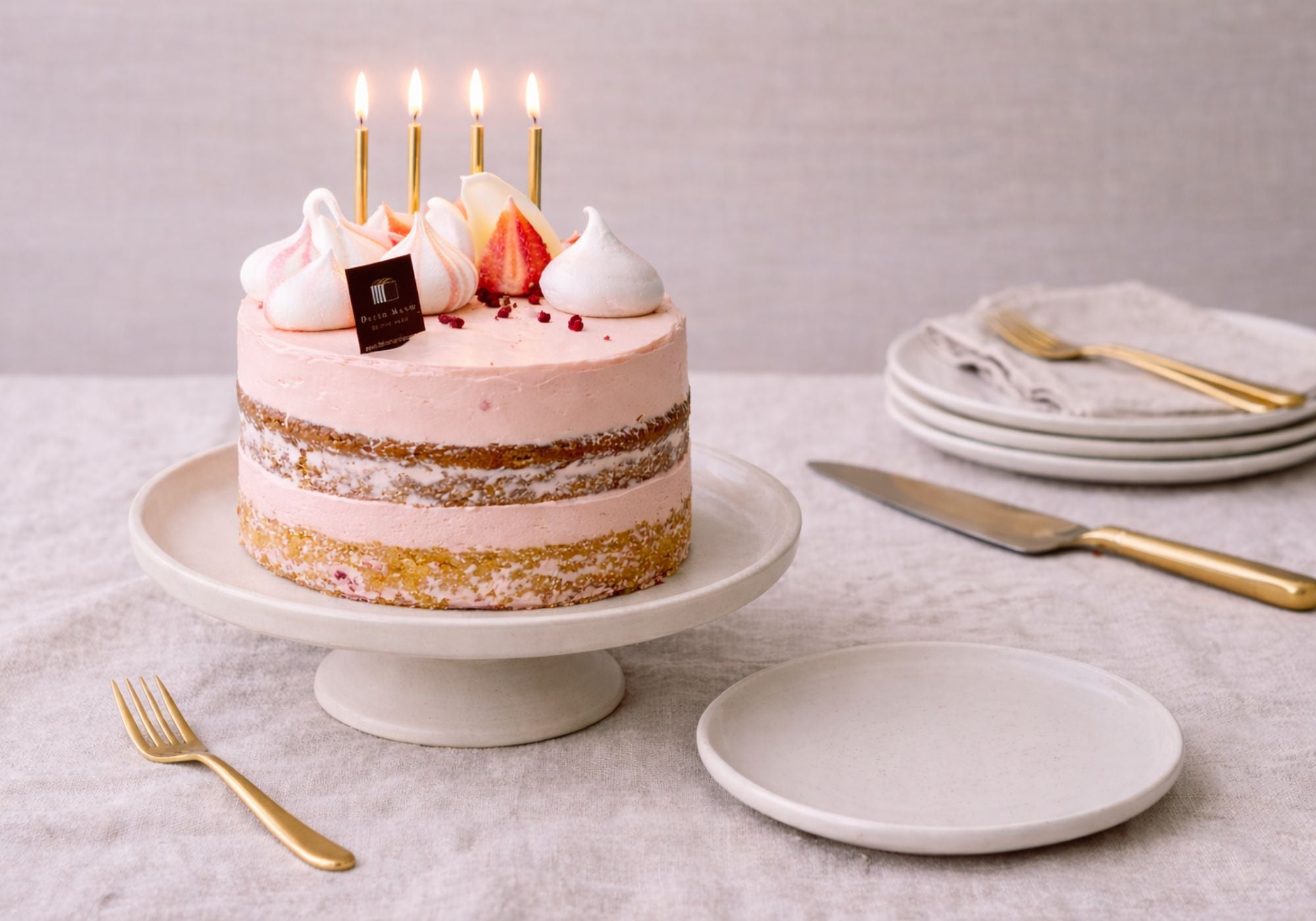 Handmade birthday cake ready for celebration on a linen table with gold candles, plates and cake knife — last minute birthday cake Brisbane.