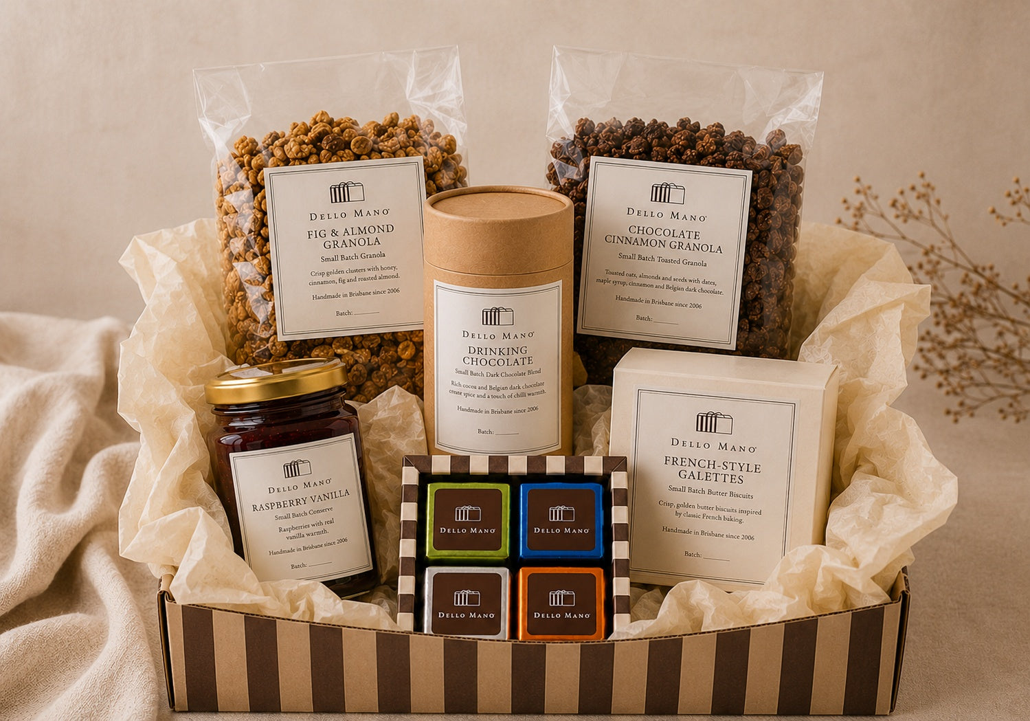 Dello Mano Slow Morning Hamper with handmade granola, Raspberry Vanilla Jam, French-Style Galettes, drinking chocolate and a four-piece mixed brownie gift box arranged in a striped hamper box with cream tissue.