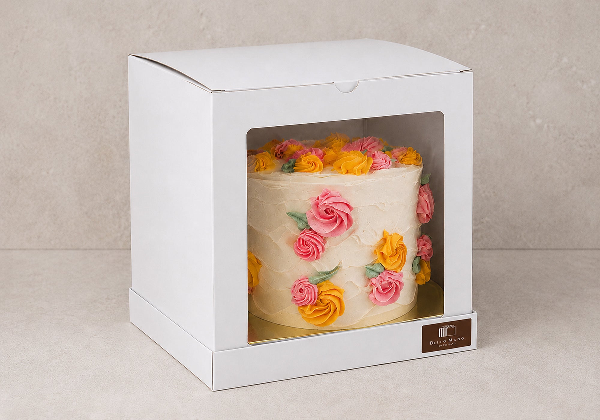 Spring Bloom Celebration Cake secured in a tall white Dello Mano cake box with a clear front window and brown logo sticker