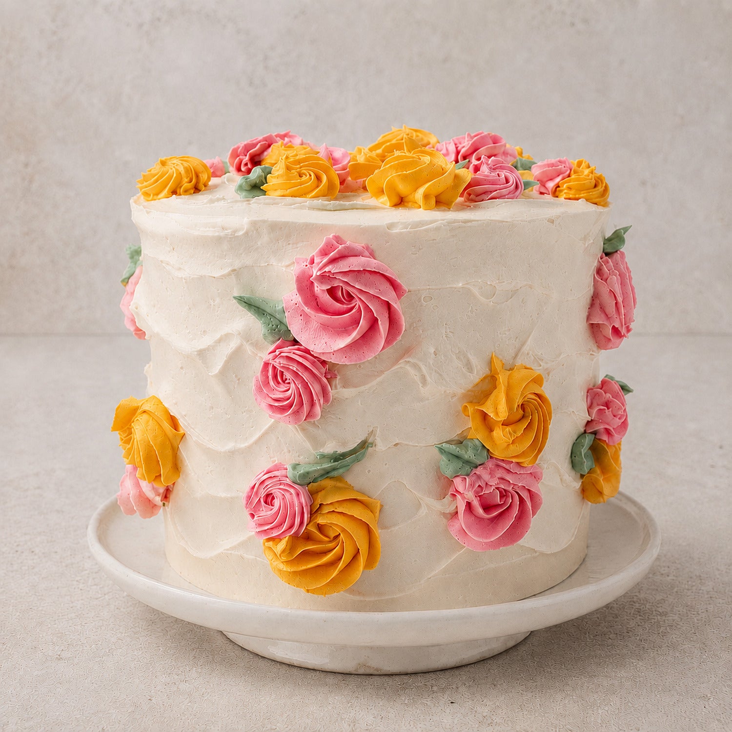 Spring Bloom vanilla celebration cake with hand-piped pink and golden Italian buttercream flowers on a handmade cake stand