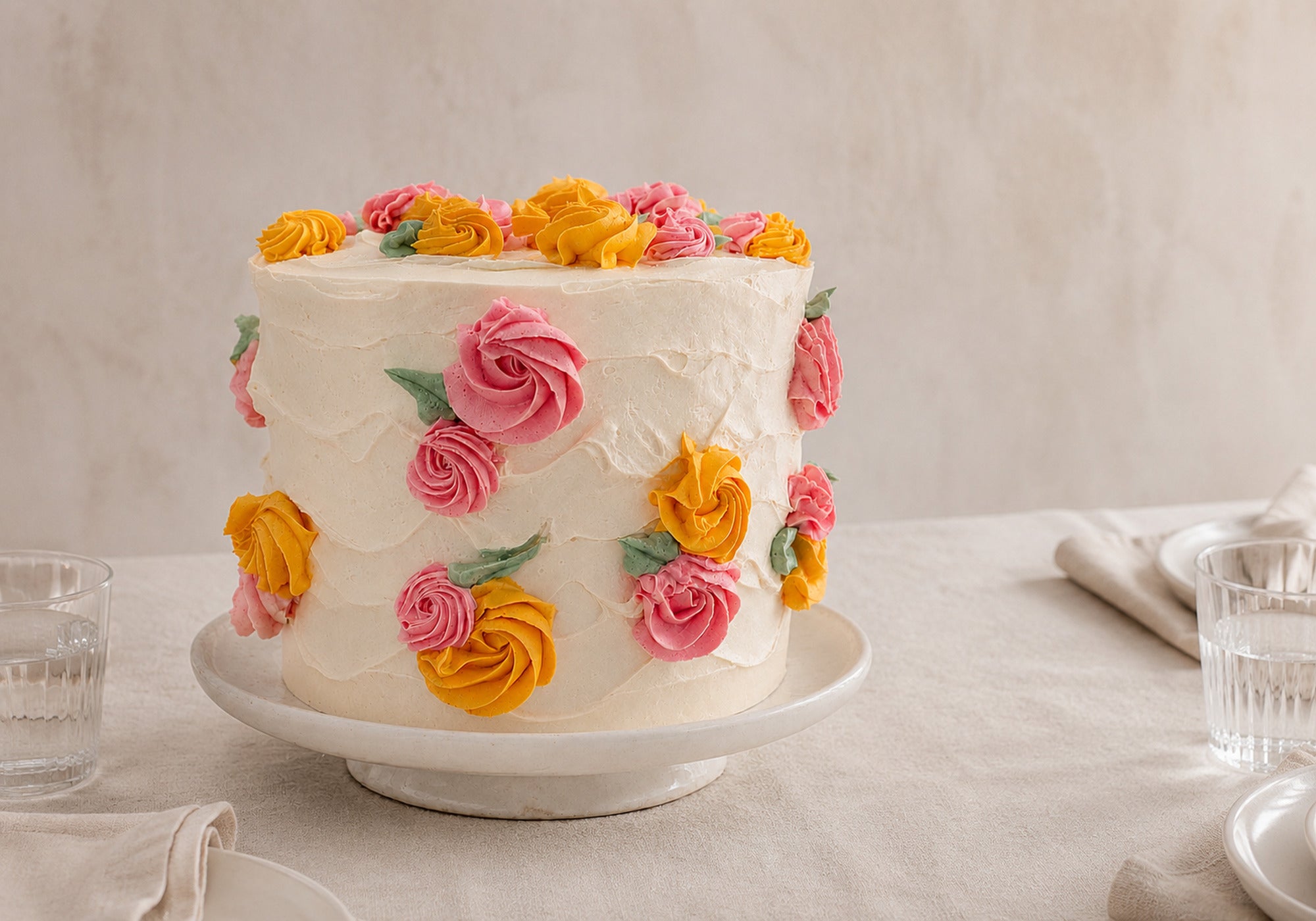 Spring Bloom vanilla celebration cake with hand-piped Italian buttercream flowers, set on a softly styled table for a gathering of approximately 20 people