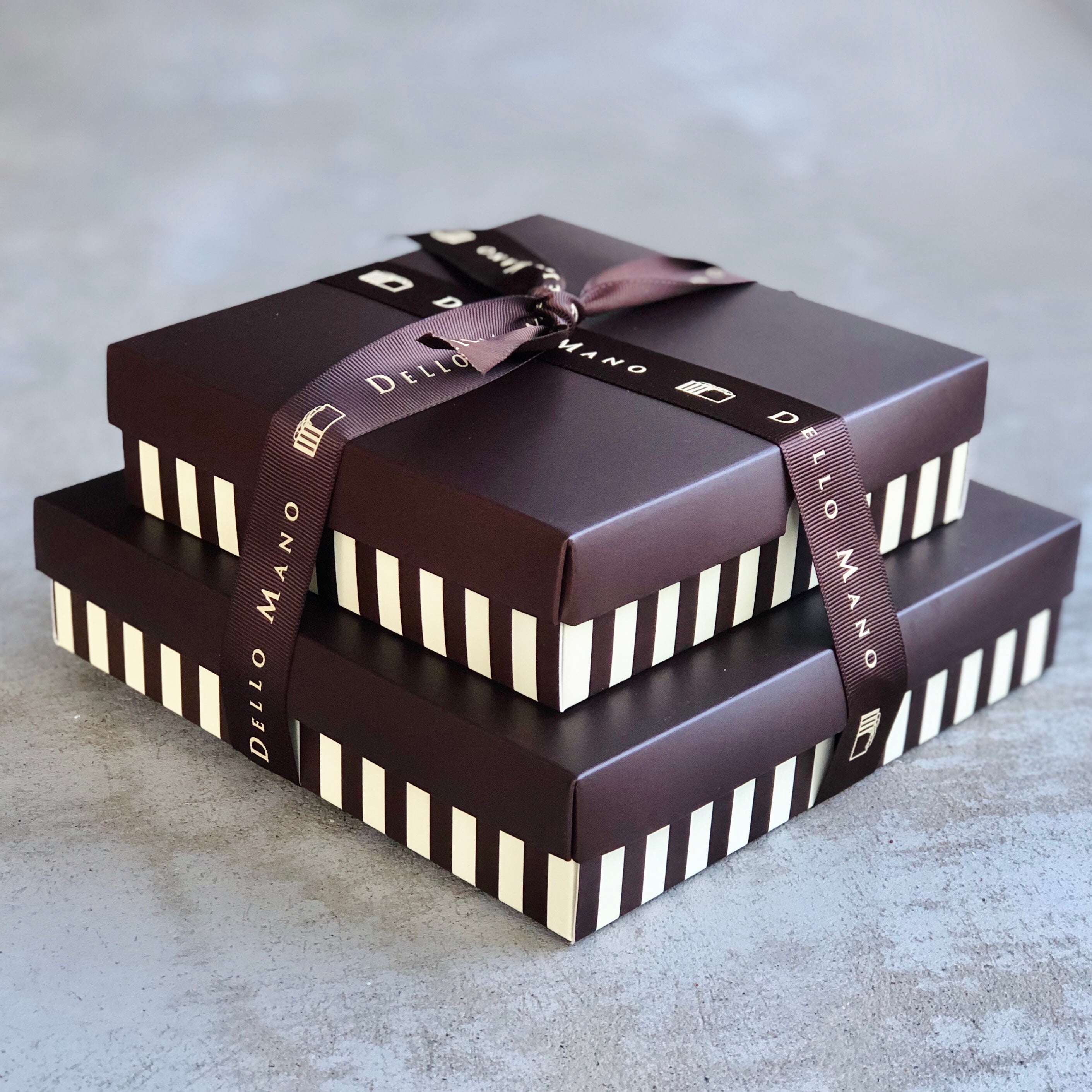 A Chocolate Gift Box delivery with a large and smaller gift box tied together with ribbon.