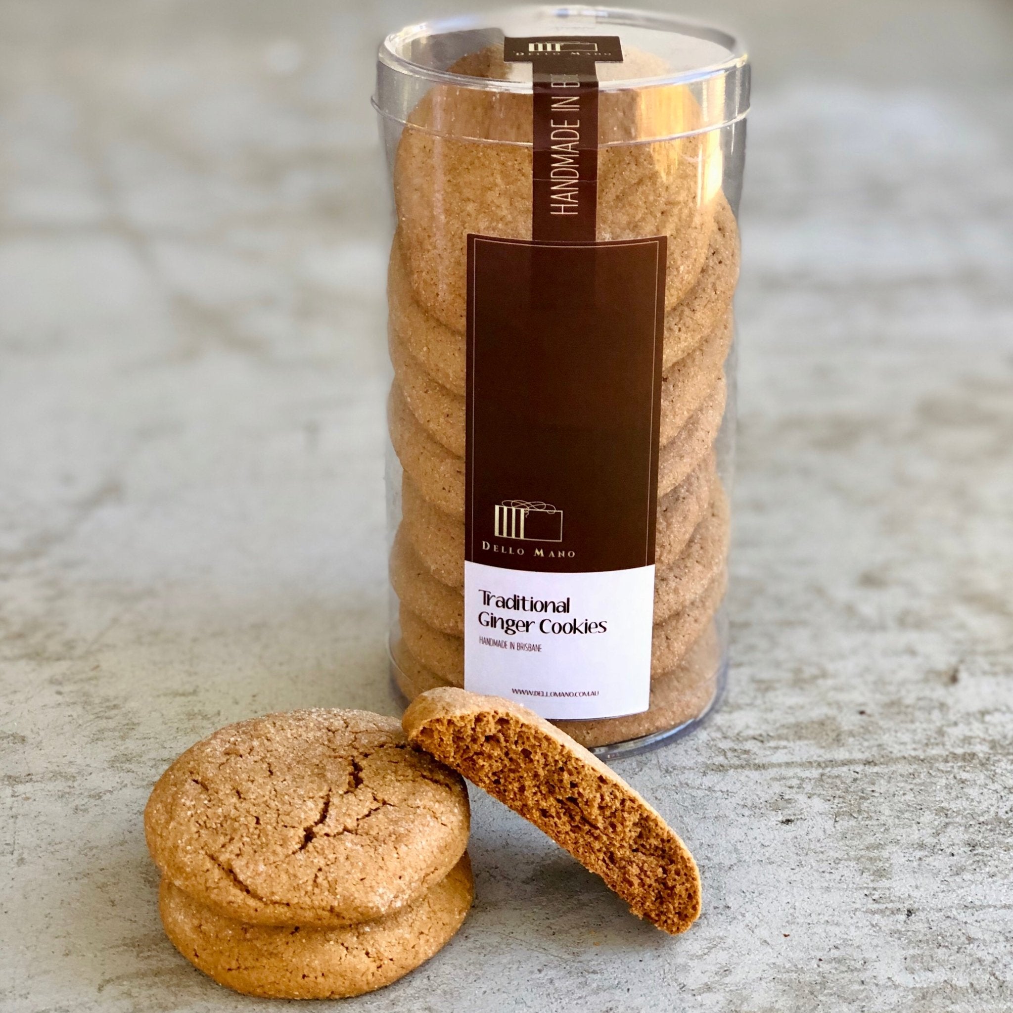 Dello Mano Traditional Ginger Nut Cookies in a tall clear pack with branded label, shown with two cookies in front including one broken to reveal the crisp spiced texture. Handmade in Brisbane, small-batch cookies for gifting or teatime.