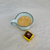 Blue cup of coffee and a Dello Mano gold foiled Luxury Brownie beside it
