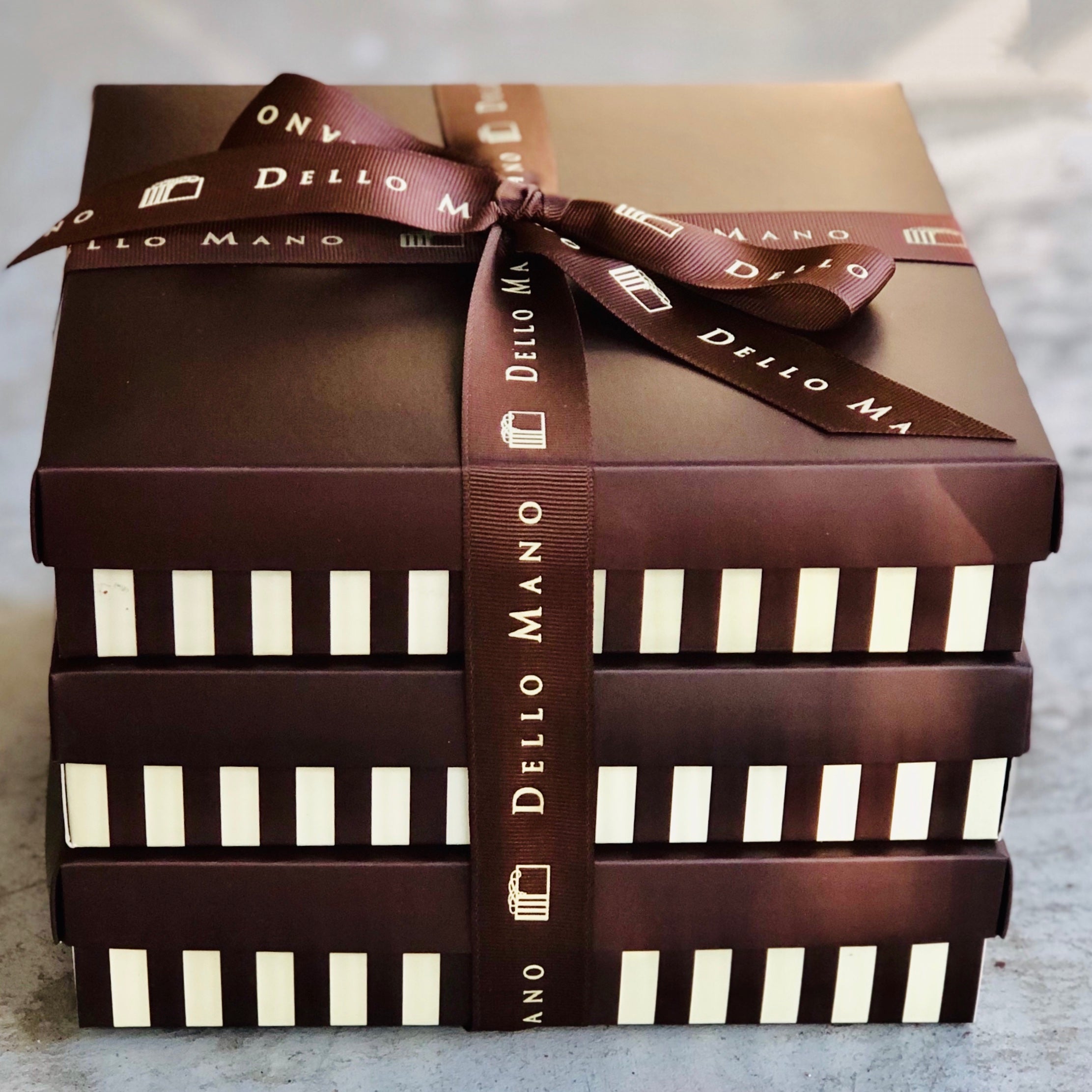 Stacked Dello Mano luxury brownie gift boxes tied with branded ribbon, ideal for premium gifting
