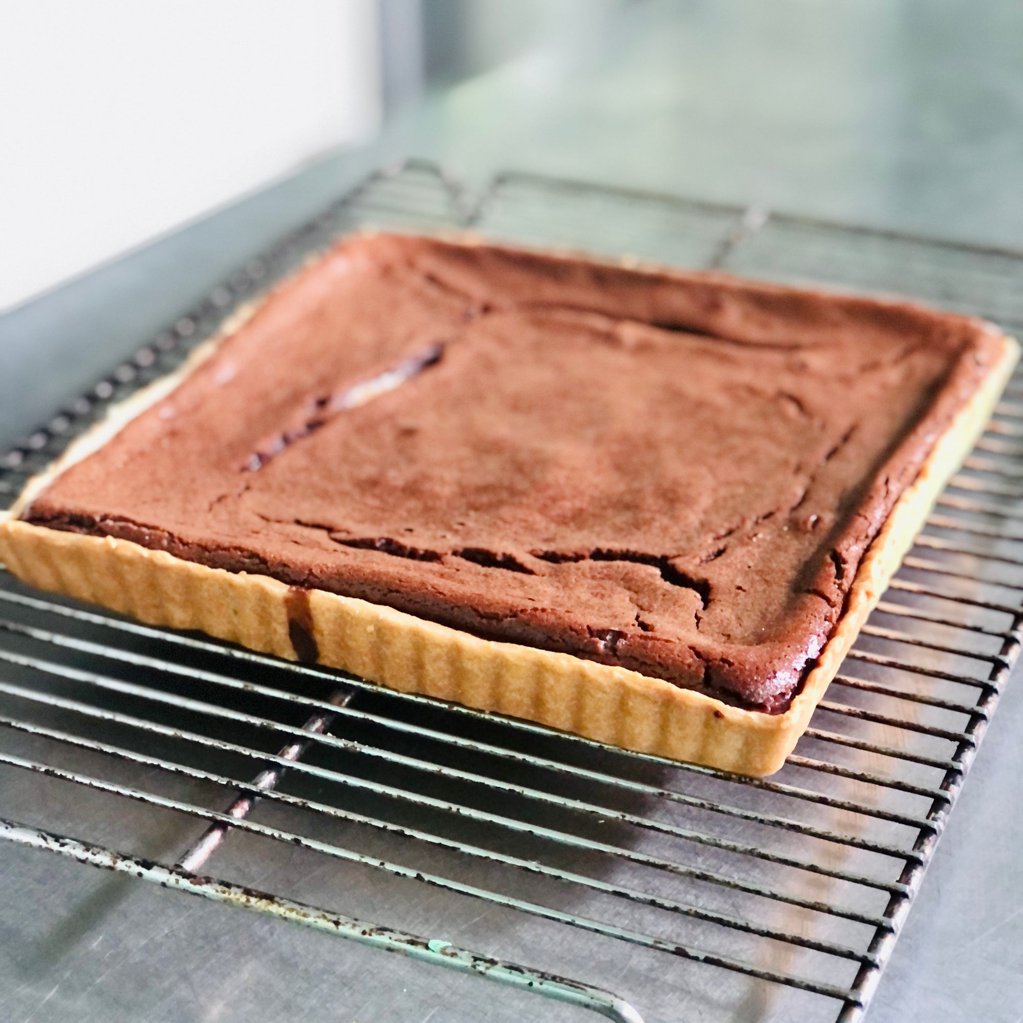 A caramel chocolate custard tart on a cooling rack