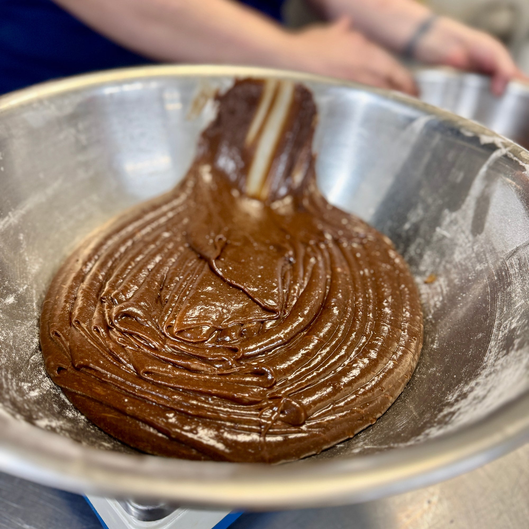 Freshly mixed small batch brownie batter in a stainless steel bowl at the Dello Mano kitchen, ready to be poured and baked.