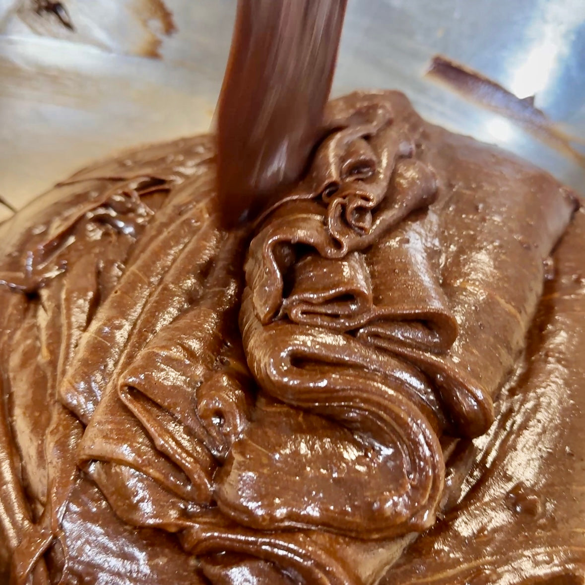 Thick Belgian chocolate brownie batter being poured by hand in Dello Mano kitchen