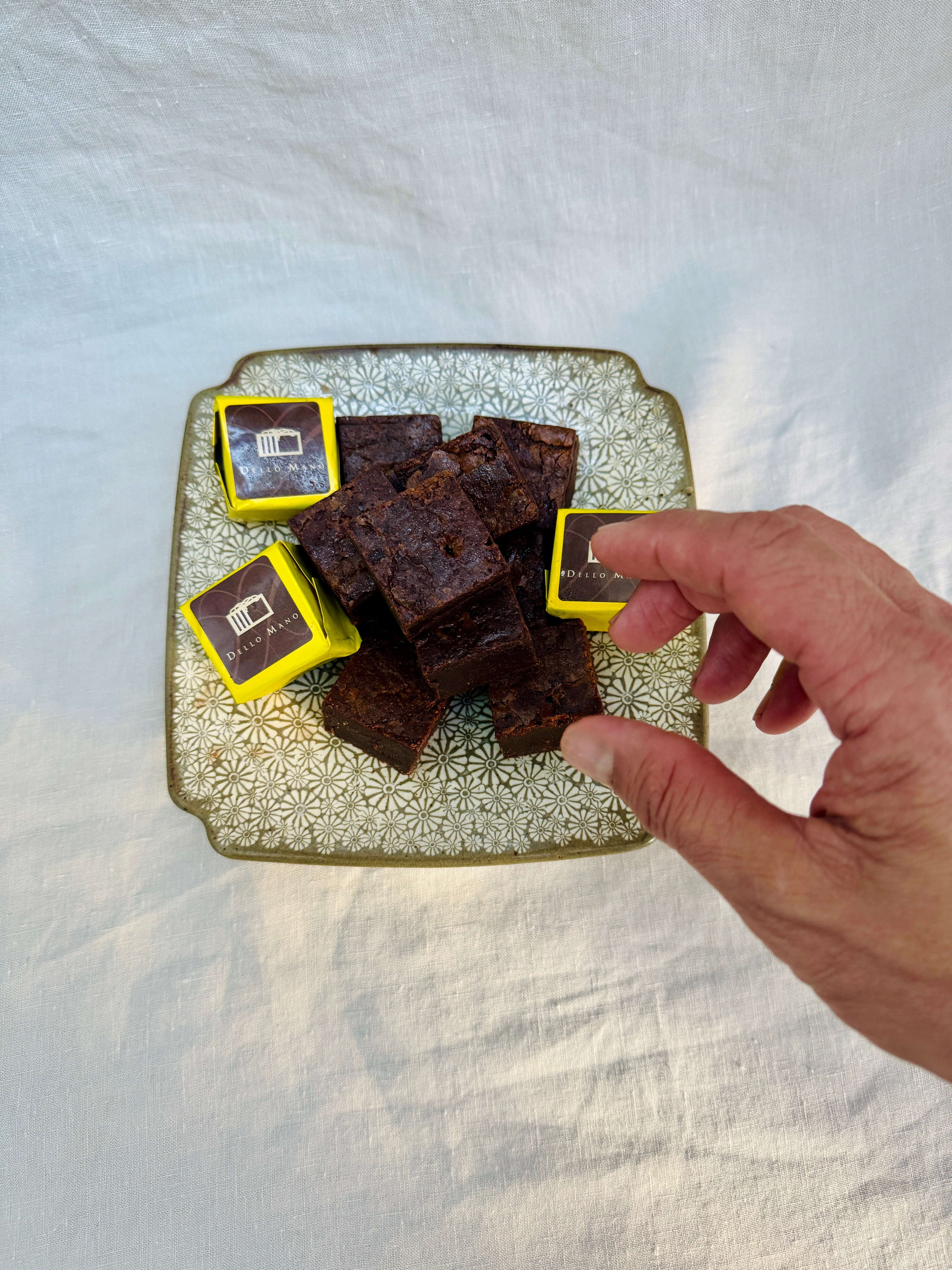 hand reaching for chocolate brownies on a plate