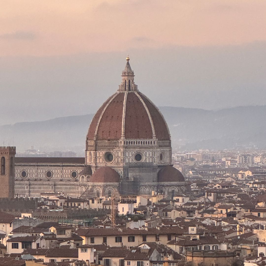Soft sunset light falling over the rooftops of Florence, highlighting the Duomo’s terracotta dome and surrounding quiet cityscape.