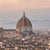 Soft sunset light falling over the rooftops of Florence, highlighting the Duomo’s terracotta dome and surrounding quiet cityscape.