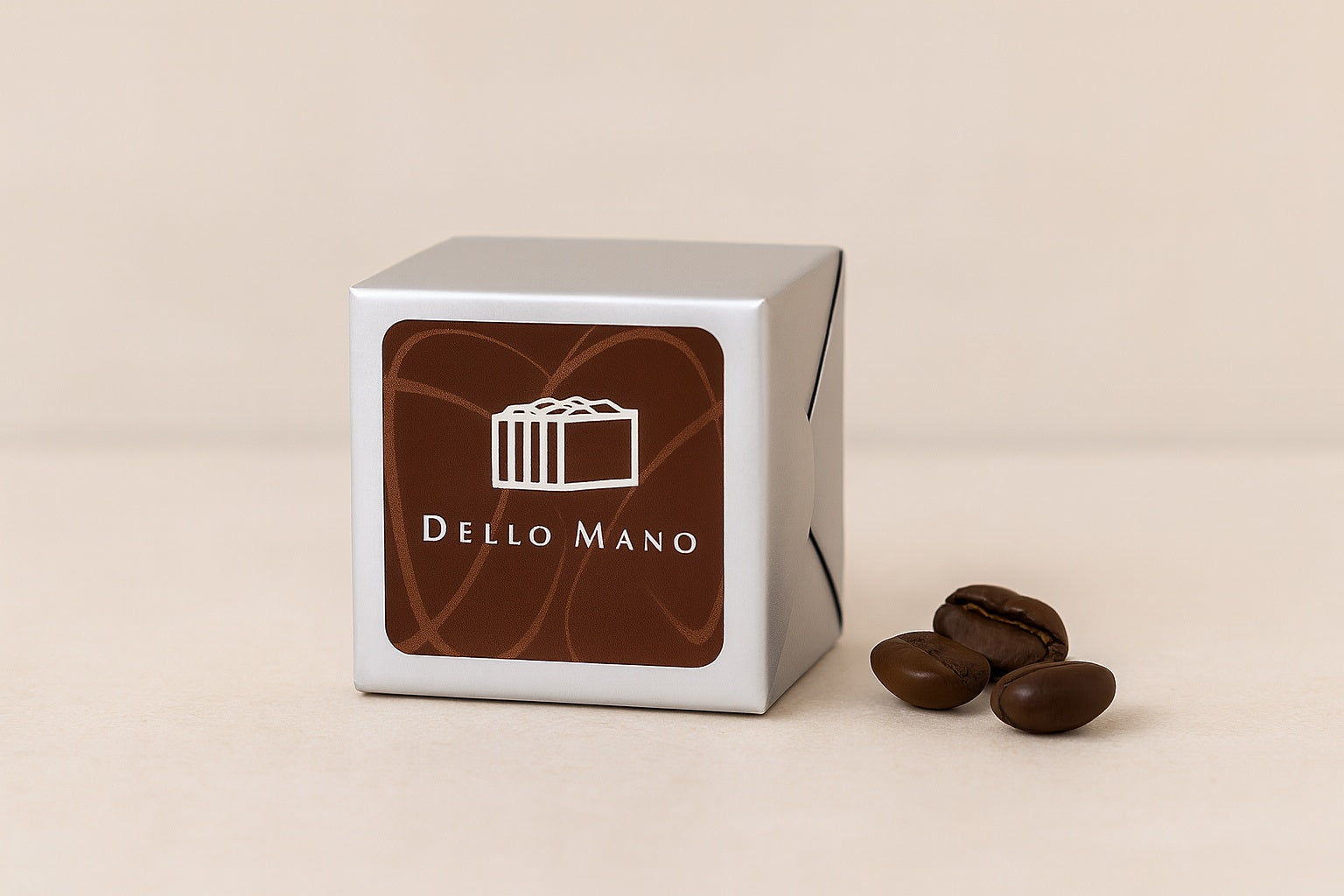 Dello Mano Espresso Walnut Brownie Cube wrapped in silver foil, displayed  with roasted coffee beans beside it.