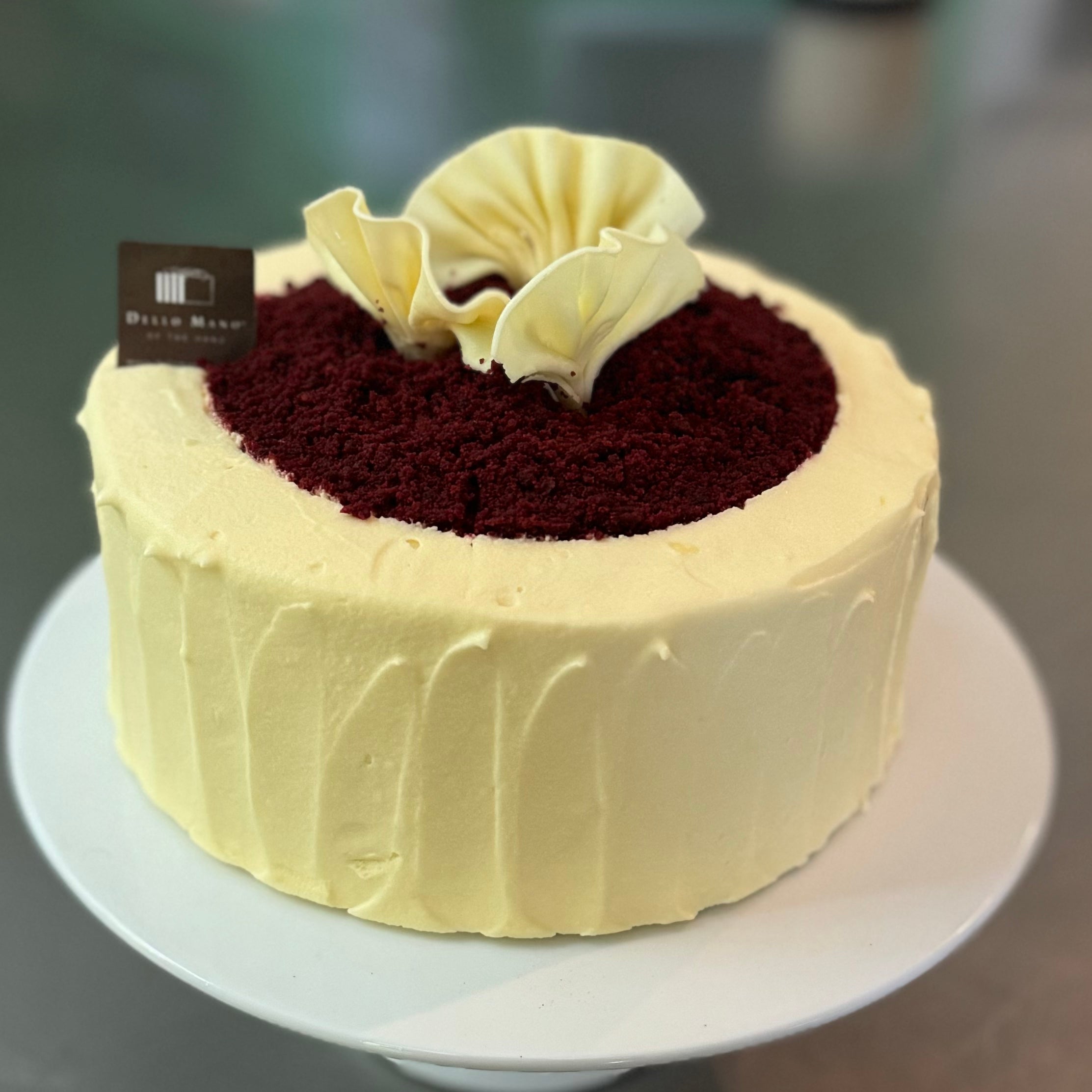 A view of the Red Velvet Cake with 3 White Chocolate handmade fans and red crumbs on top