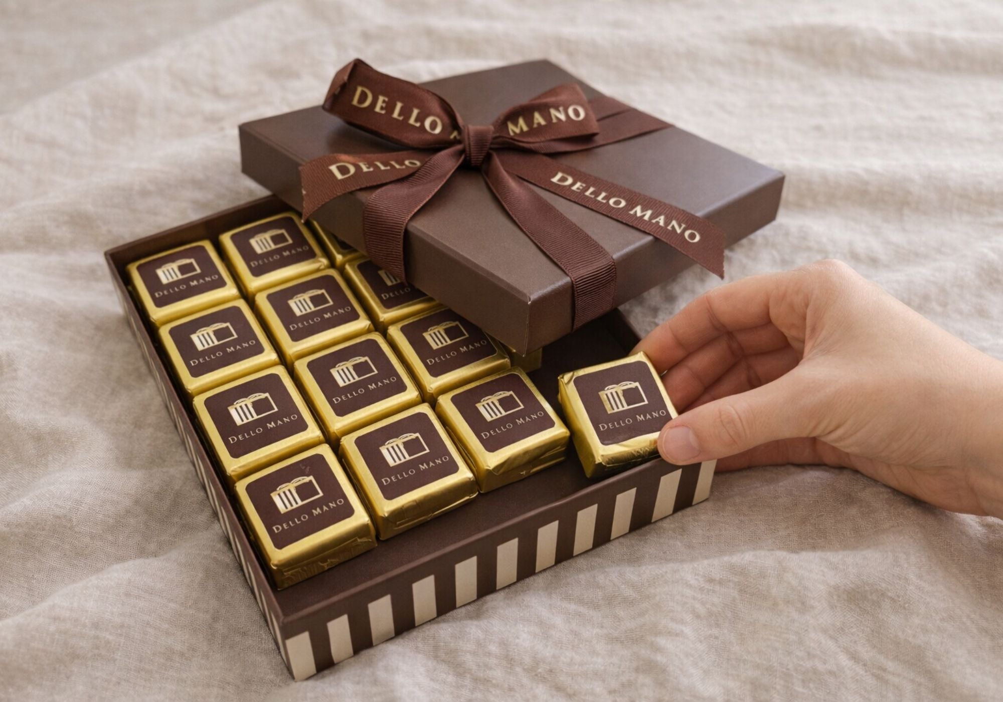 Hand reaching into a Dello Mano handmade brownie gift box, showing small-batch chocolate brownies prepared and wrapped by hand for birthday delivery Australia-wide
