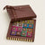 Dello Mano 16-piece luxury brownie gift box with signature ribbon and assorted foil-wrapped flavours, displayed on a soft off-white background.
