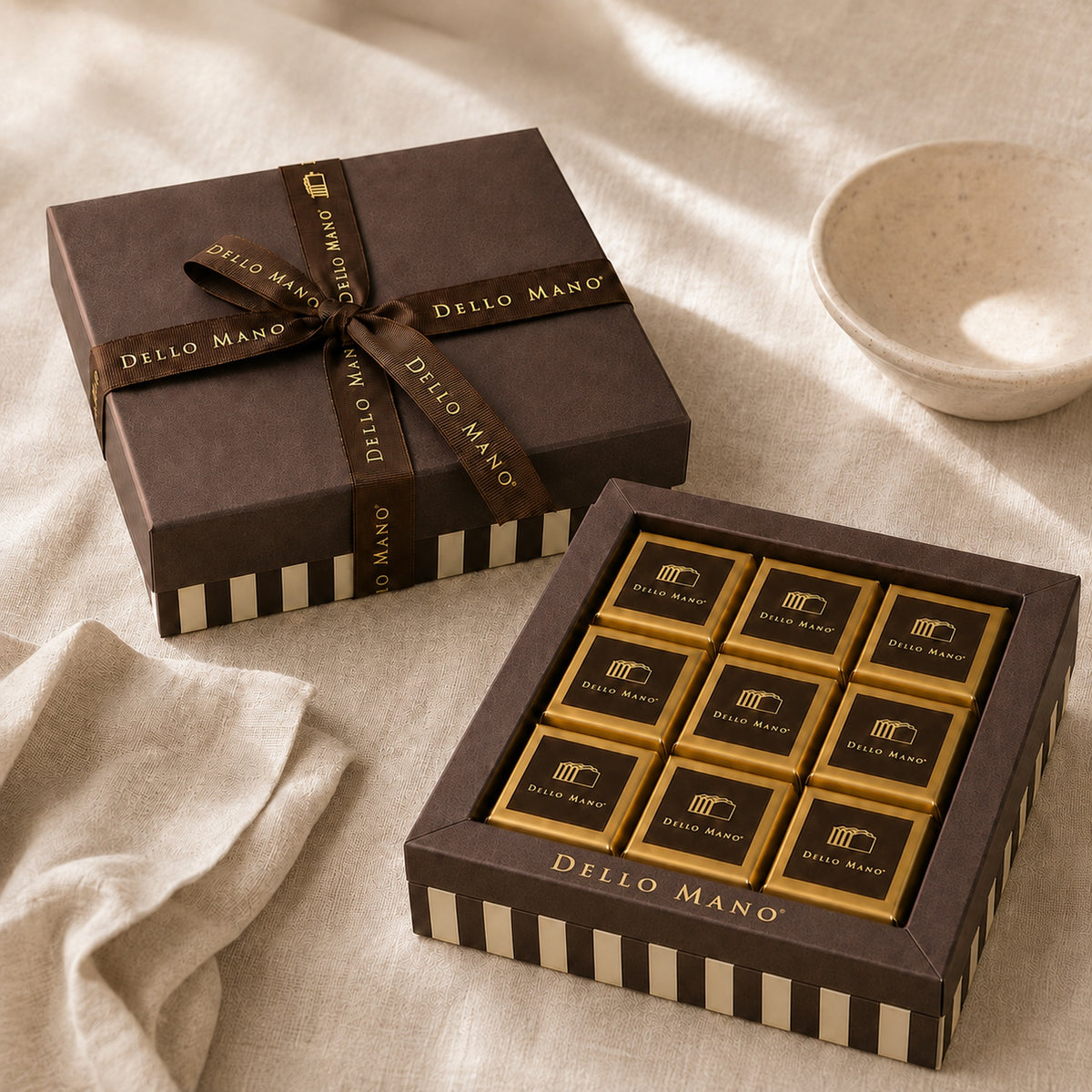 Dello Mano Signature Classic chocolate gift box with gold-wrapped handmade brownies, presented open and ribboned on soft cream linen.