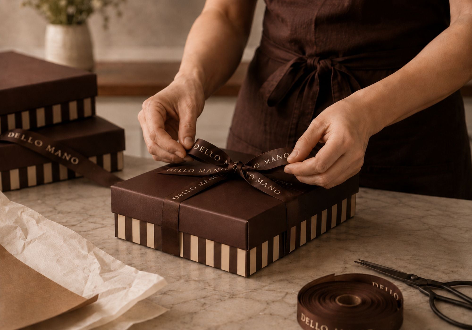 Dello Mano gift box being tied by hand with signature brown ribbon 