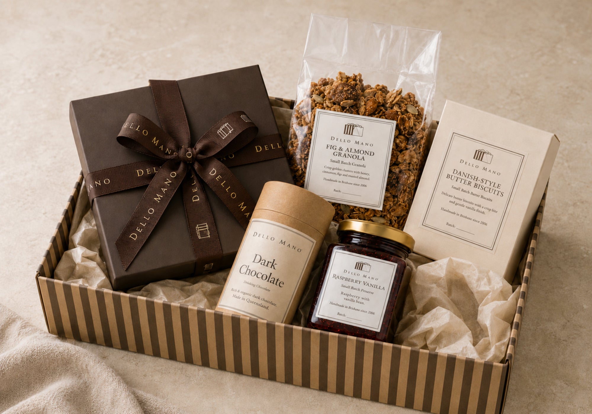 Open Dello Mano corporate hamper with handmade brownies, biscuits, granola, preserve and drinking chocolate in a striped recyclable gift box.
