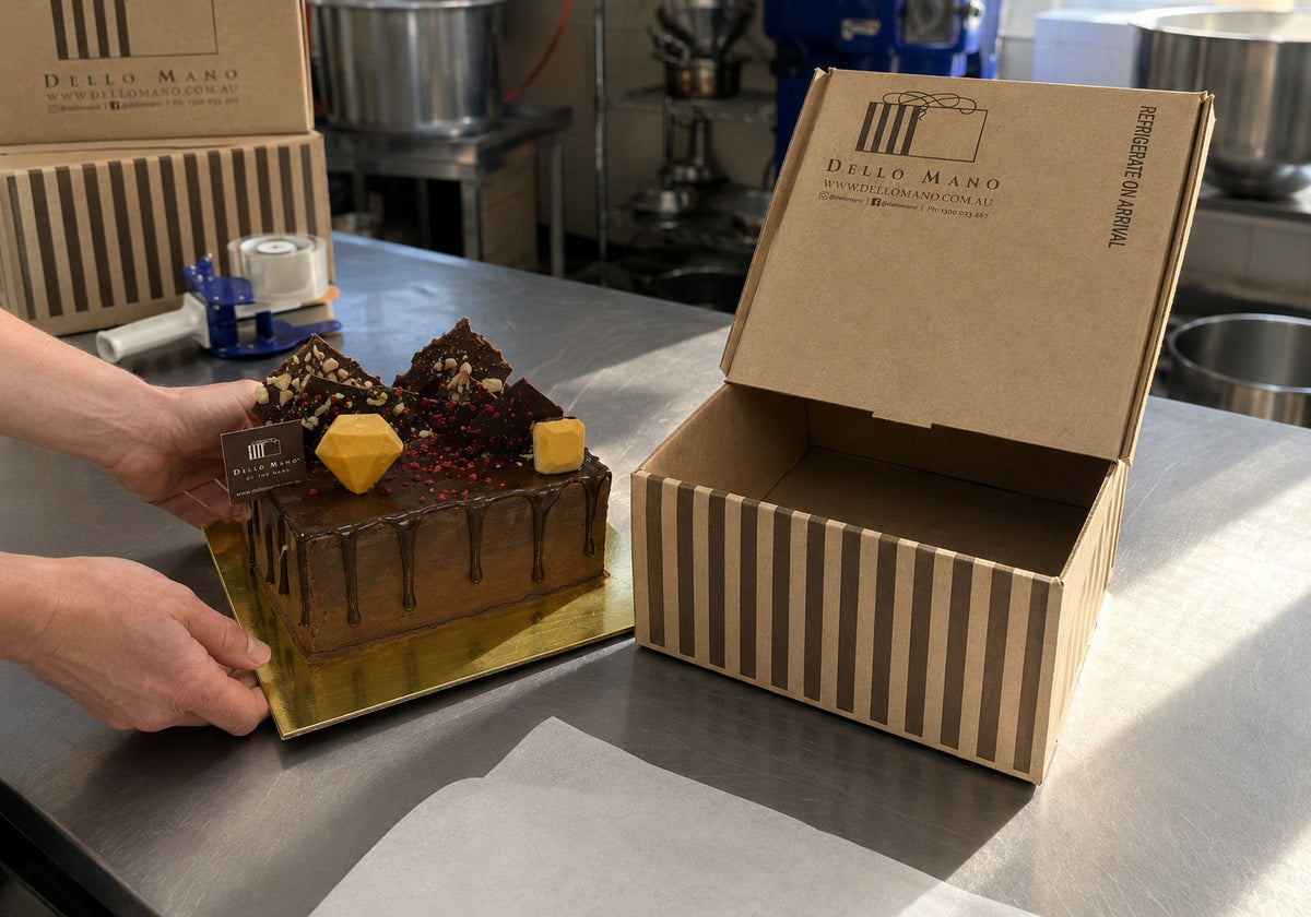 Dello Mano handmade chocolate cake being prepared for door-to-door delivery in the Brisbane kitchen beside its striped cake box.