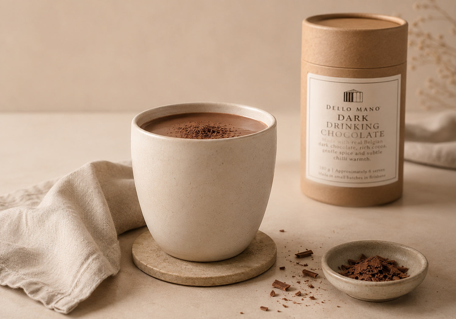 Dello Mano Dark Drinking Chocolate made with real Belgian dark chocolate, served in a latte-coloured ceramic cup beside the 180 g canister in a calm neutral setting.
