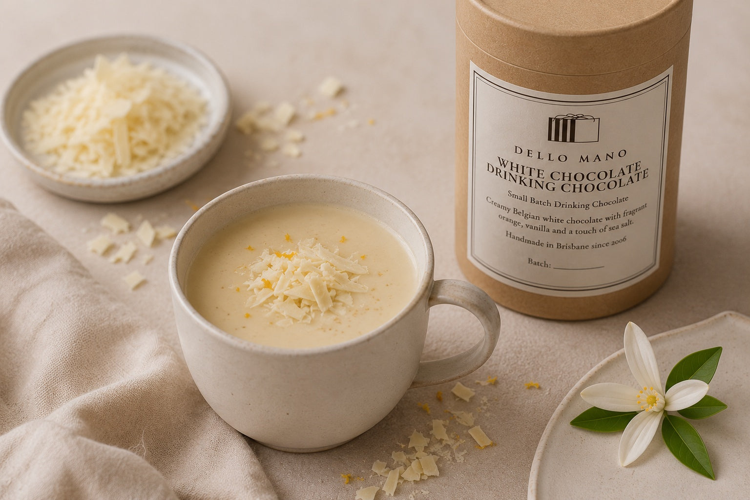 Dello Mano White Chocolate Drinking Chocolate served in a modern ceramic cup with white chocolate shavings, beside the 180 g canister in a calm neutral setting.