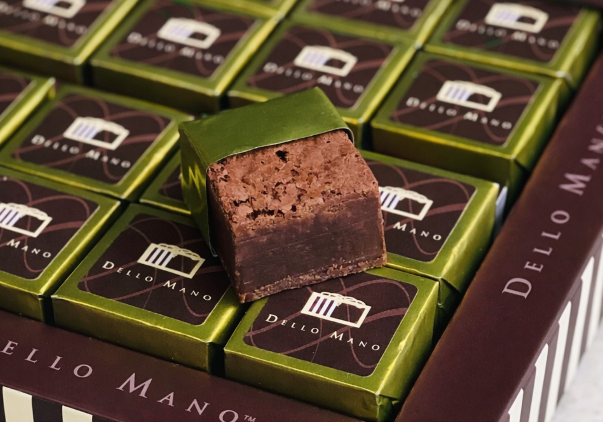 Dello Mano handmade chocolate brownie cube with rich fudgy texture displayed on gold foil wrapped brownies 