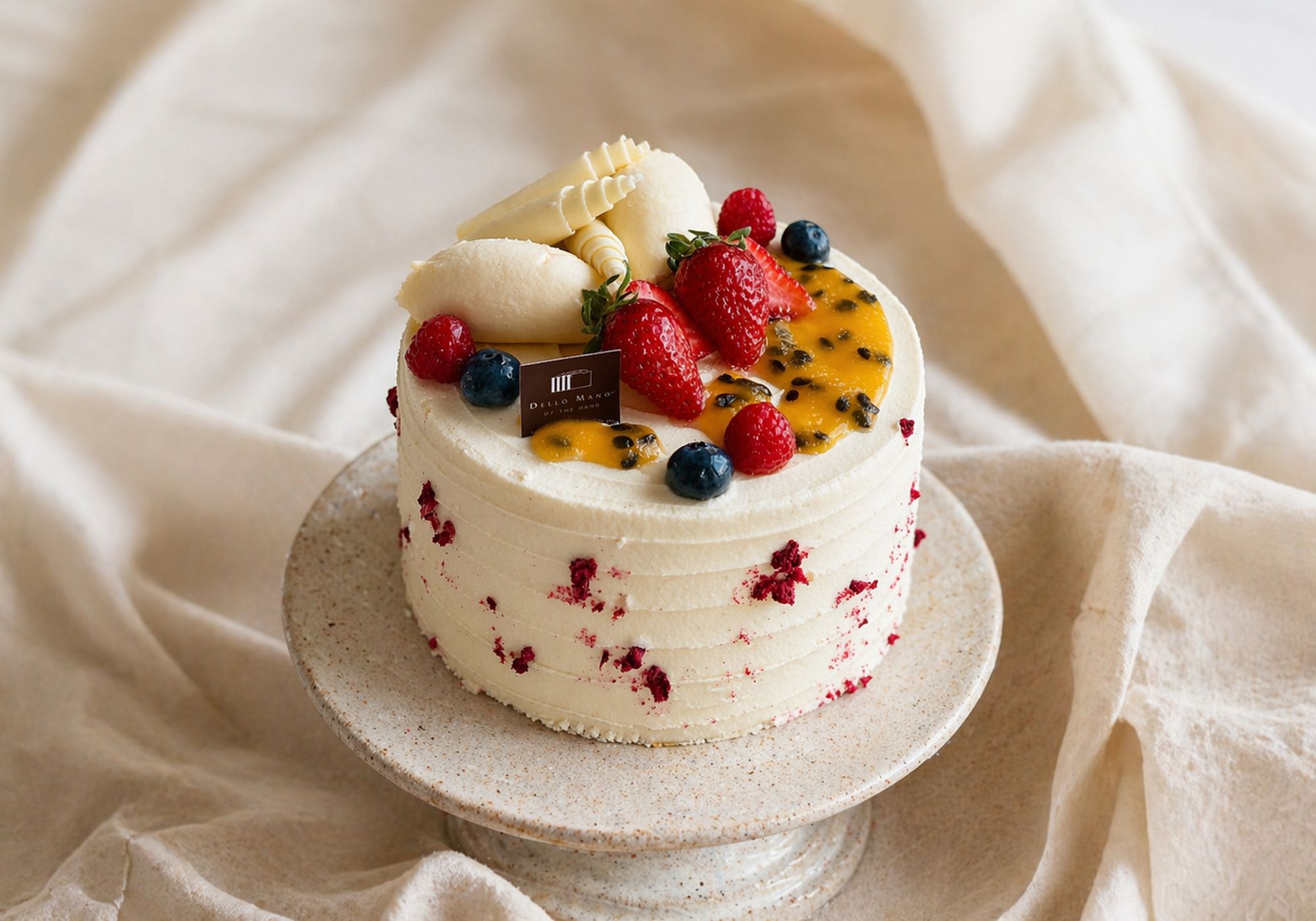 handmade cake Brisbane showing clean structure and smooth finish on ceramic stand styled on soft linen