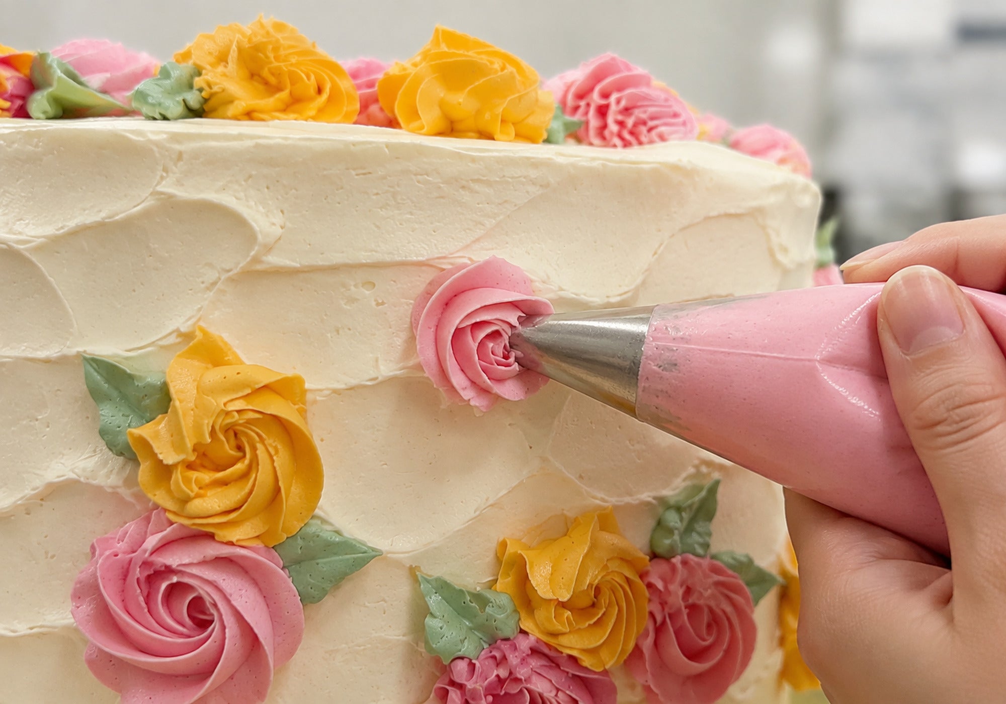 Edible pink Italian buttercream flower being piped by hand onto the Spring Bloom Celebration Cake