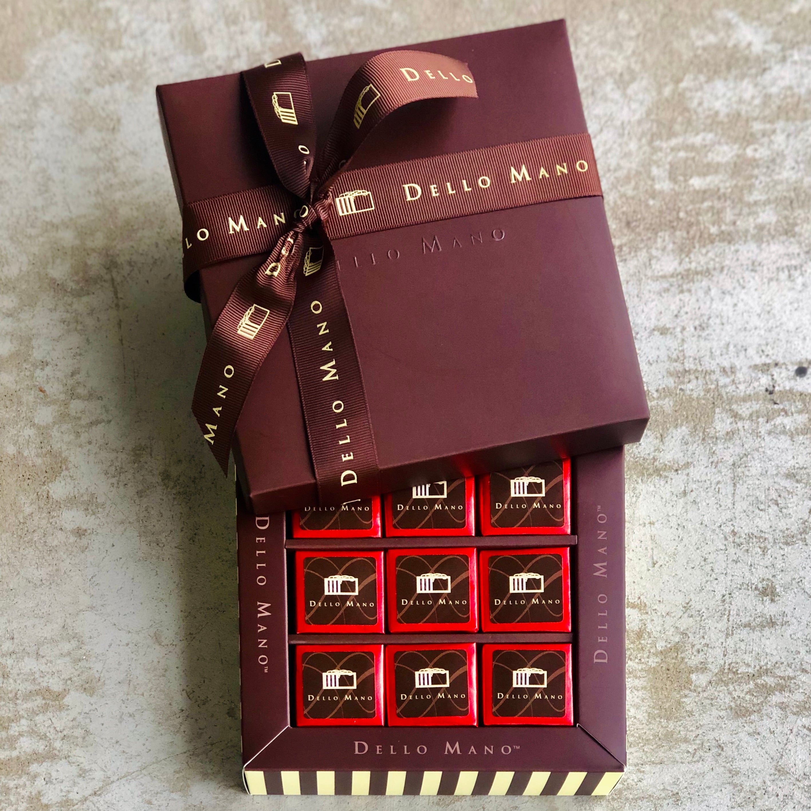 Nine gluten free brownies in a chocolate gift box with lid and ribbon