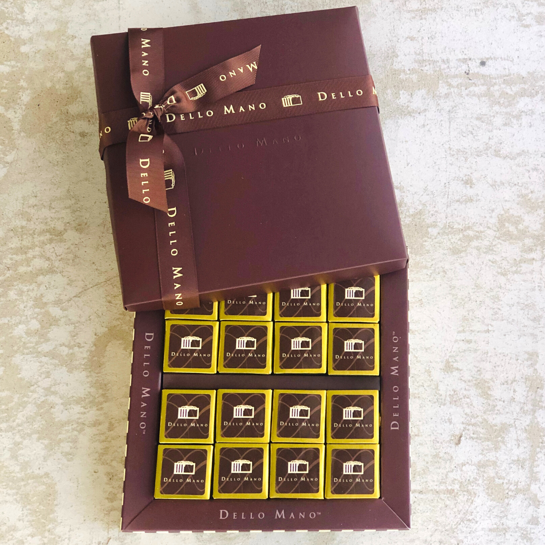 Luxury Dello Mano 16-piece brownie gift box opened to display individually wrapped gourmet chocolate squares.