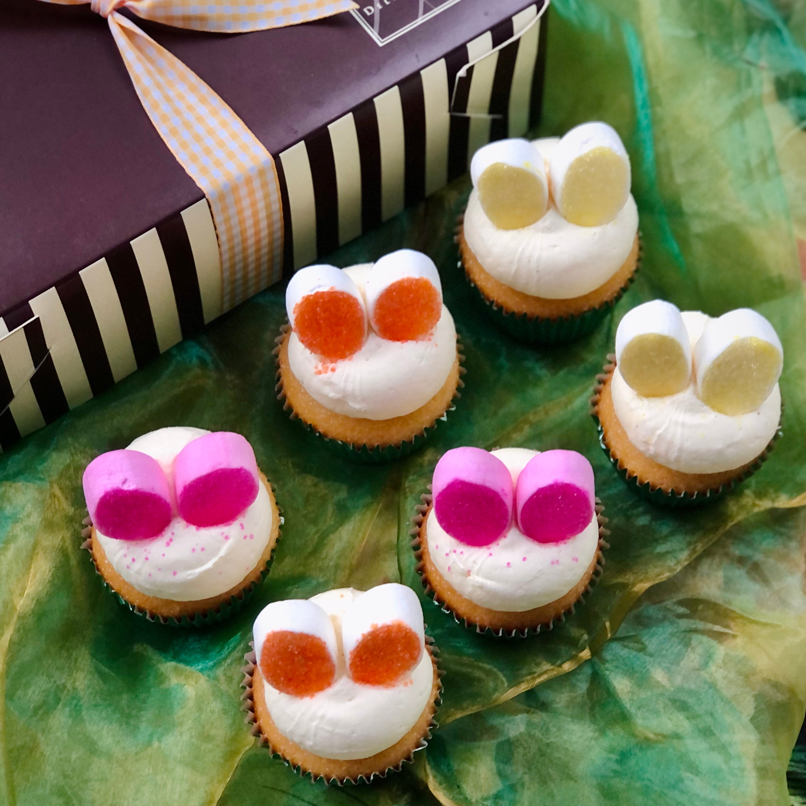 An Easter Cupcake Gift box with six colourful Easter Bunny Cupcakes in front.