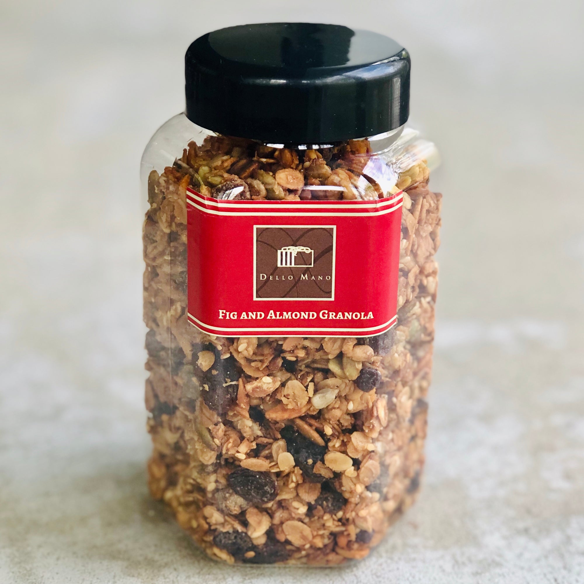 A jar of granola with red label that says Dello Mano Fig and Almond Granola