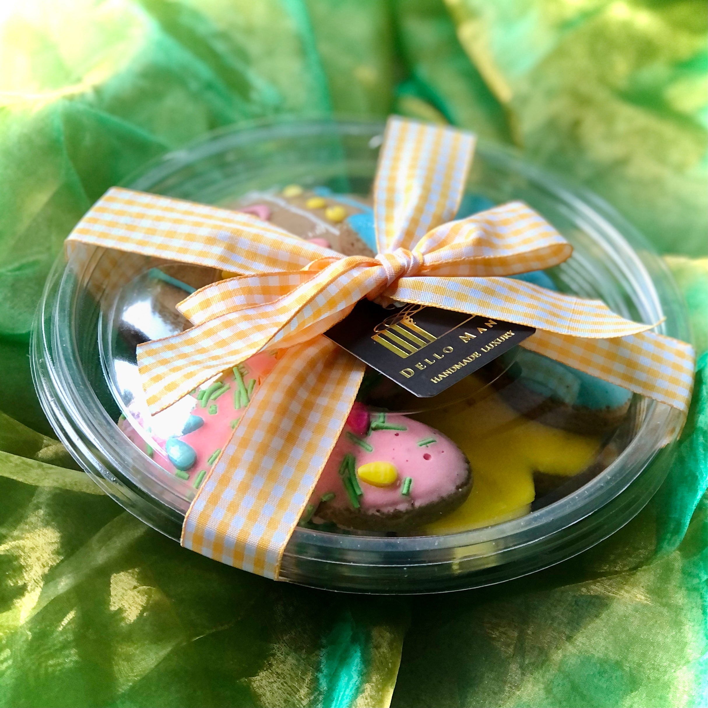 A gift box of easter cookies finished with ribbon and bow on a green fabric background