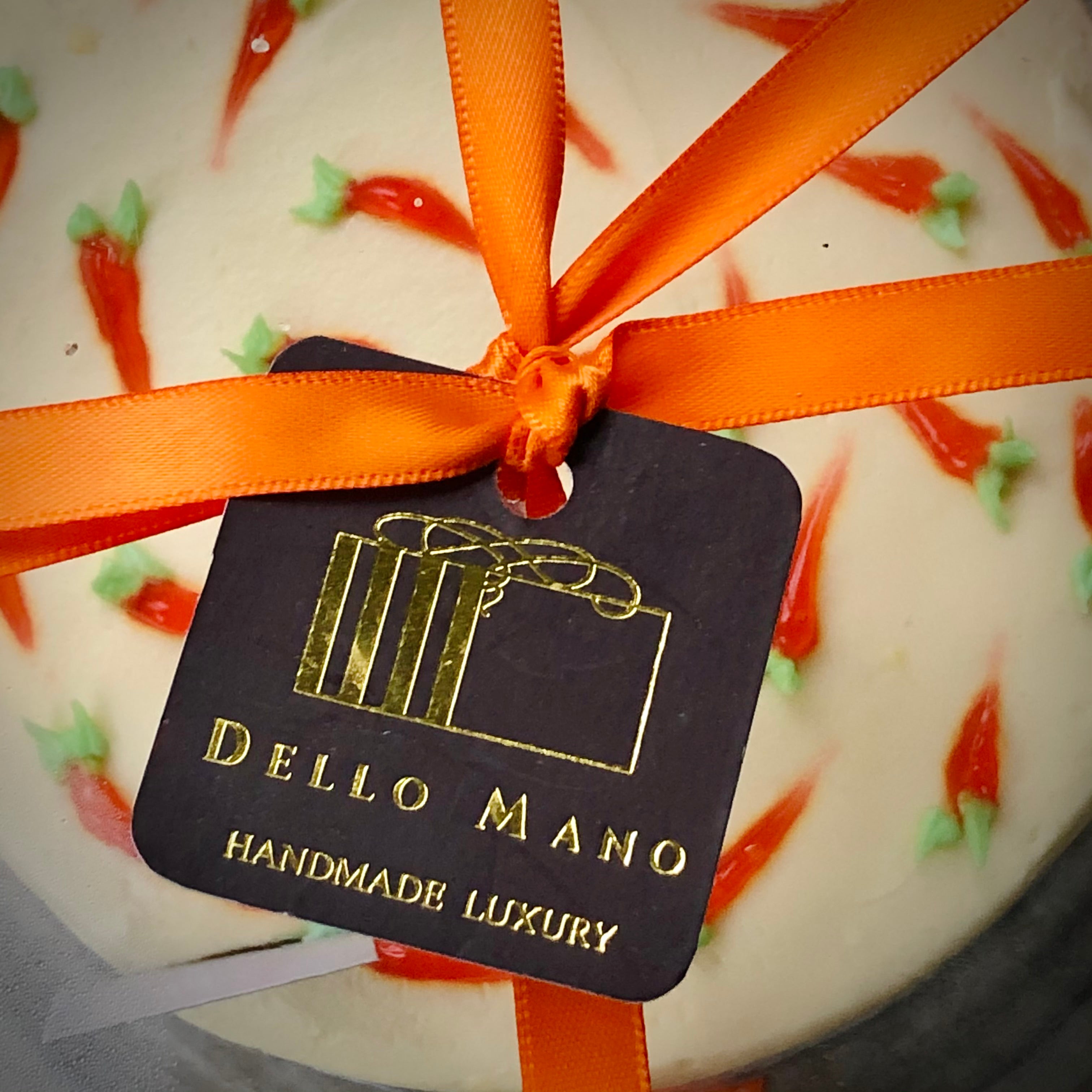 Close up view of the top of the Easter Carrot Cake with ribbon tie and a tag with Dello Mano logo
