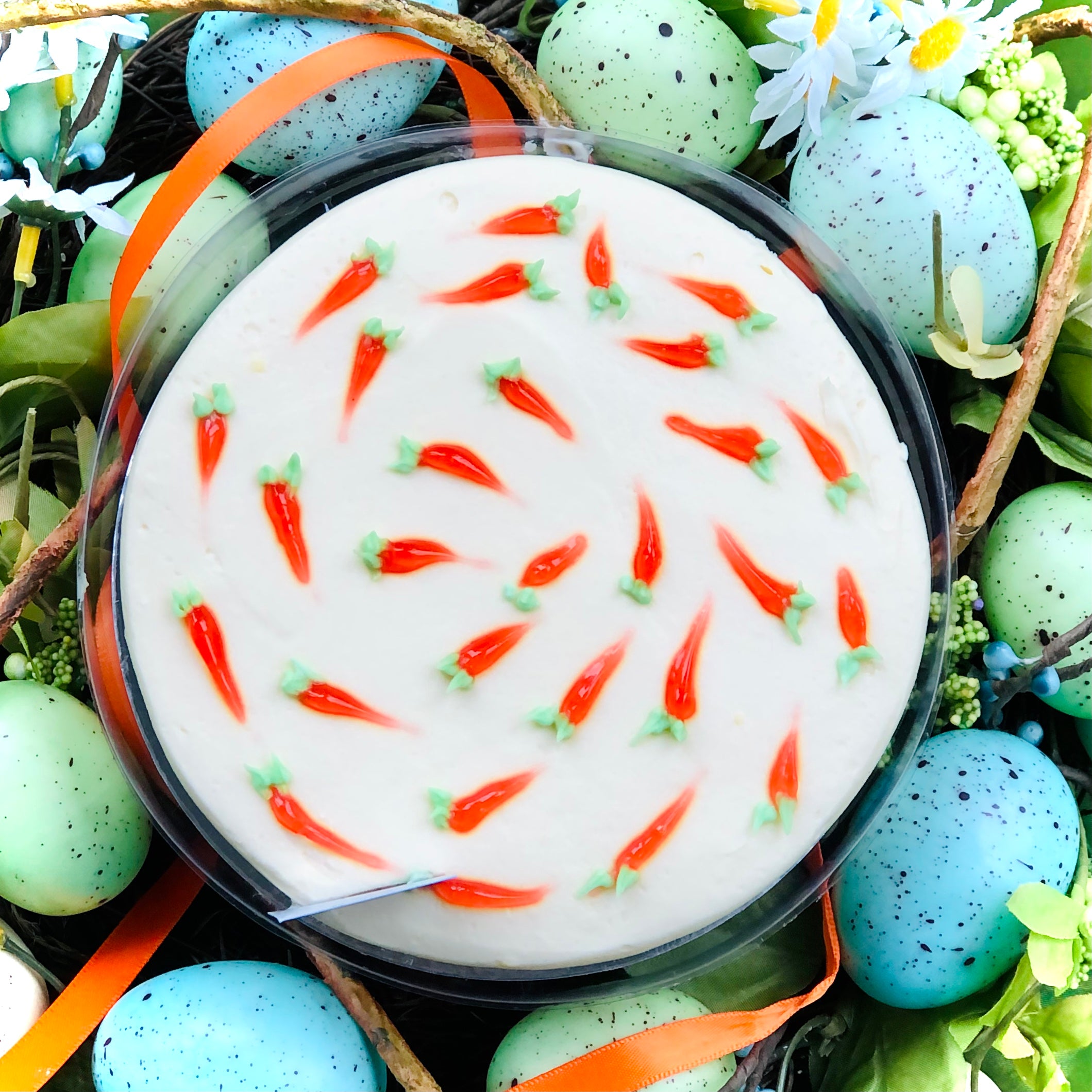 Impressionistic orange carrots on top of an Easter Carrot Cake sitting within blue green eggs.