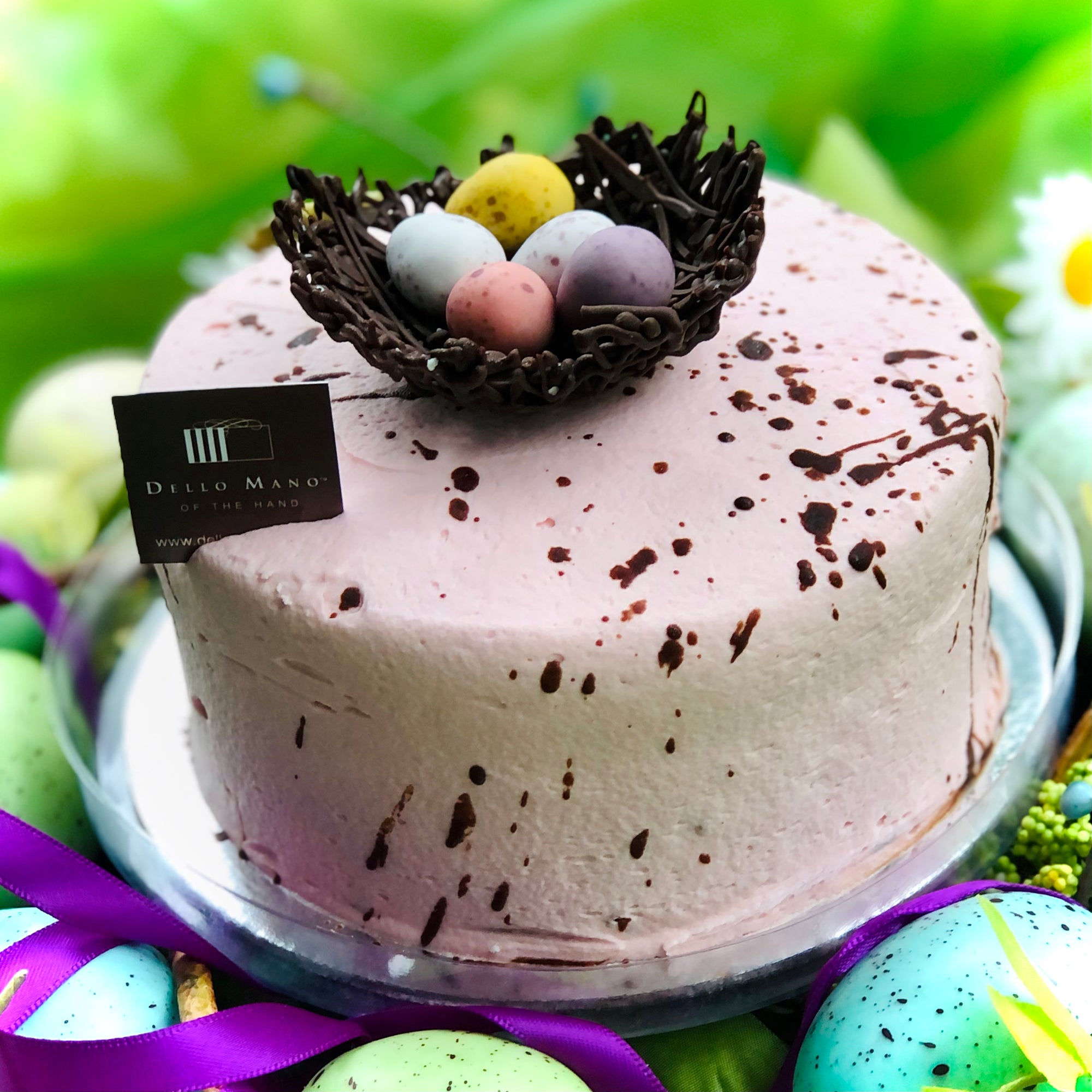 A dusty pink speckled Easter Egg Nest Cake sitting on top