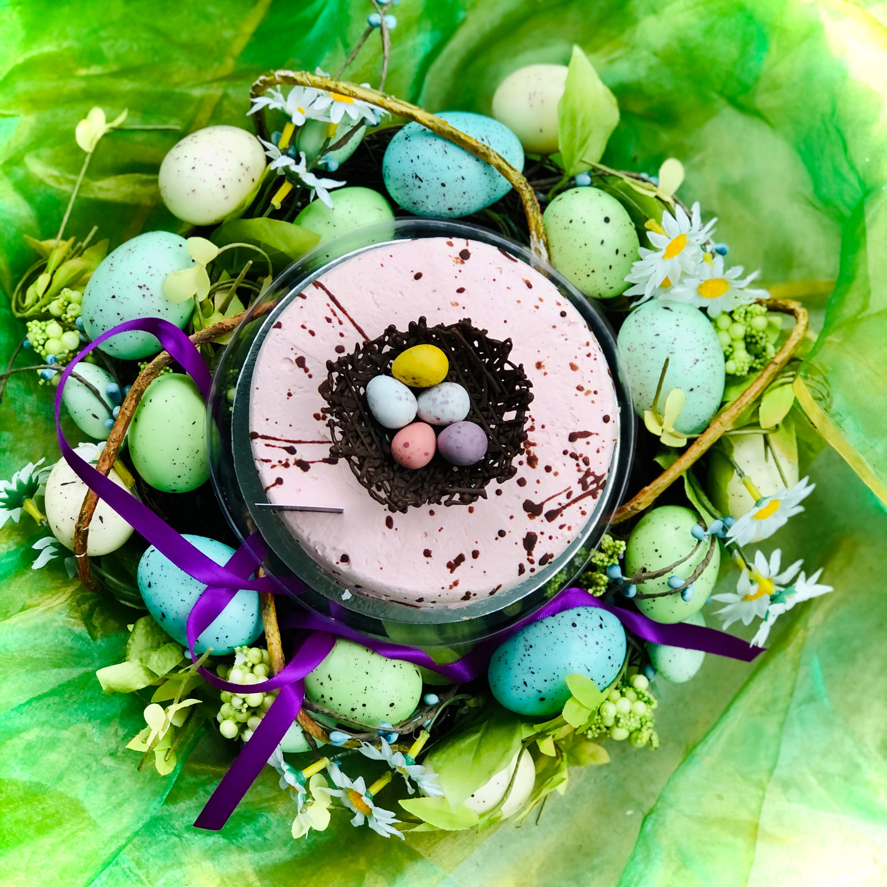 A top view of easter eggs sitting in a chocolate nest and surrounded by blue-green eggs